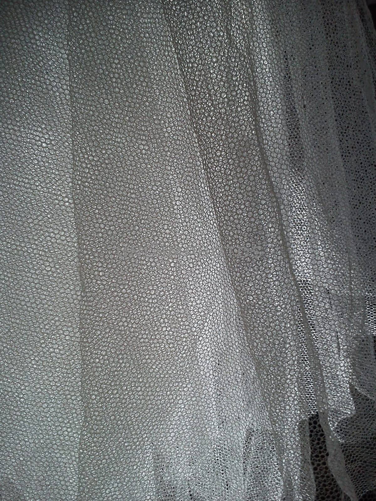 White wrinkled mesh fabric. A washable thing made of synthetic material. Mosquito net folded into soft folds. Fabric similar to a bridal veil.