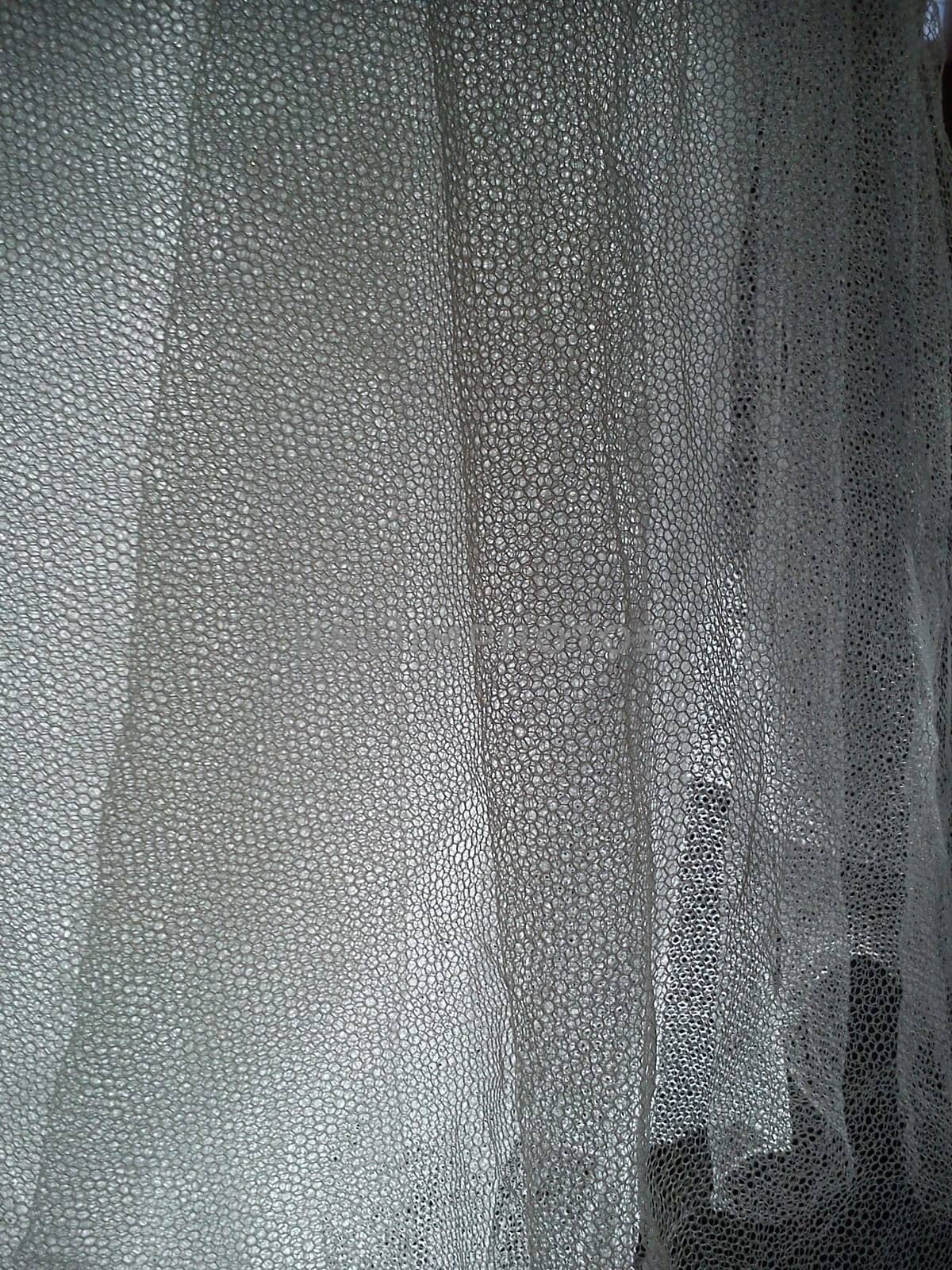 White wrinkled mesh fabric. A washable thing made of synthetic material. Mosquito net folded into soft folds. Fabric similar to a bridal veil.
