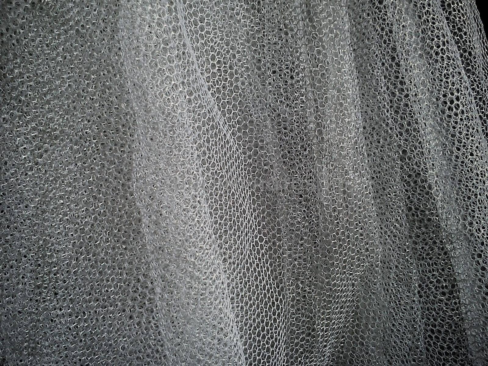 White wrinkled mesh fabric. A washable thing made of synthetic material. Mosquito net folded into soft folds. Fabric similar to a bridal veil.