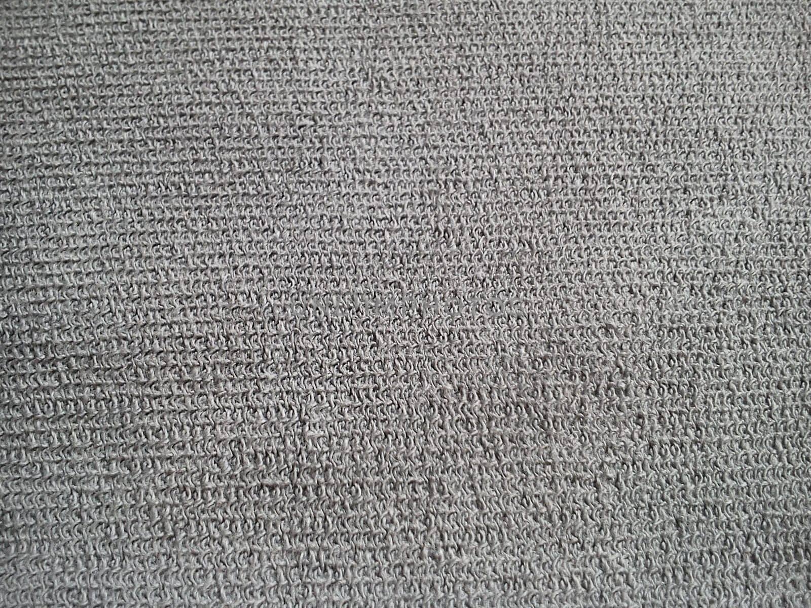 Gray cotton or linen. Separate threads and weaves are noticeable. Gray nondescript background. Sewing universal material. Fine knit machine knitting.