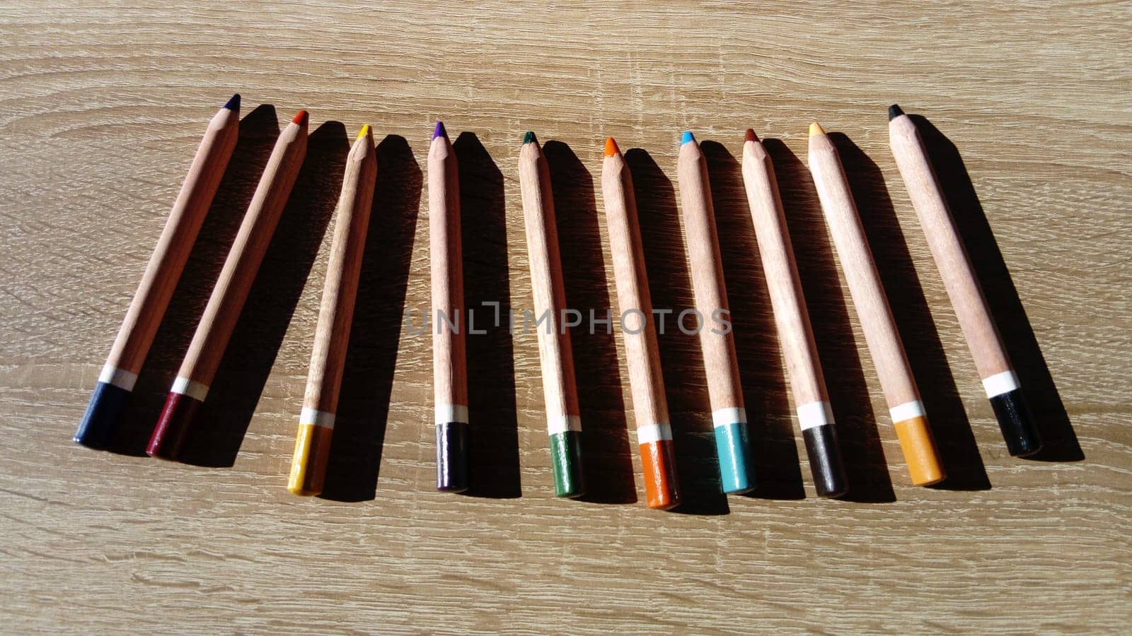 On a wooden table are wooden thick colored pencils