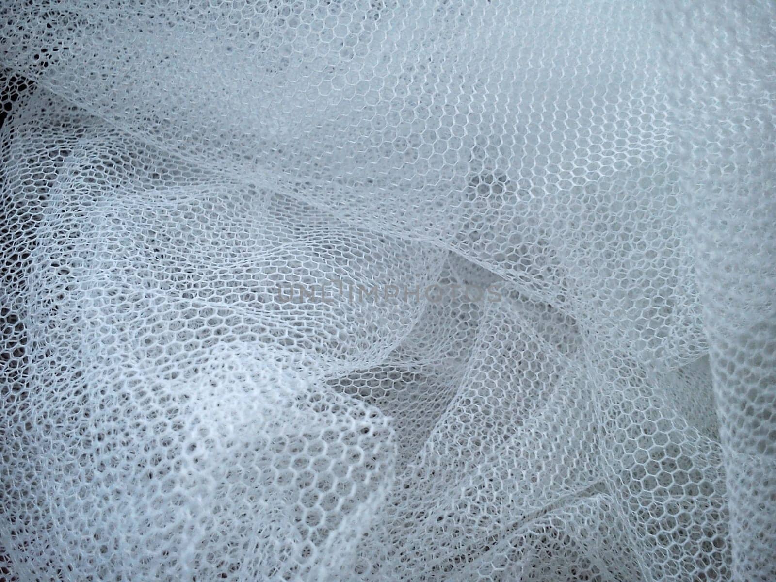 White wrinkled mesh fabric. A washable thing made of synthetic material. Mosquito net folded into soft folds. Fabric similar to a bridal veil.