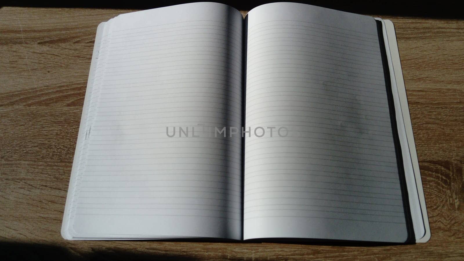 U-turn notebook with blank white pages. Harsh natural sunlight