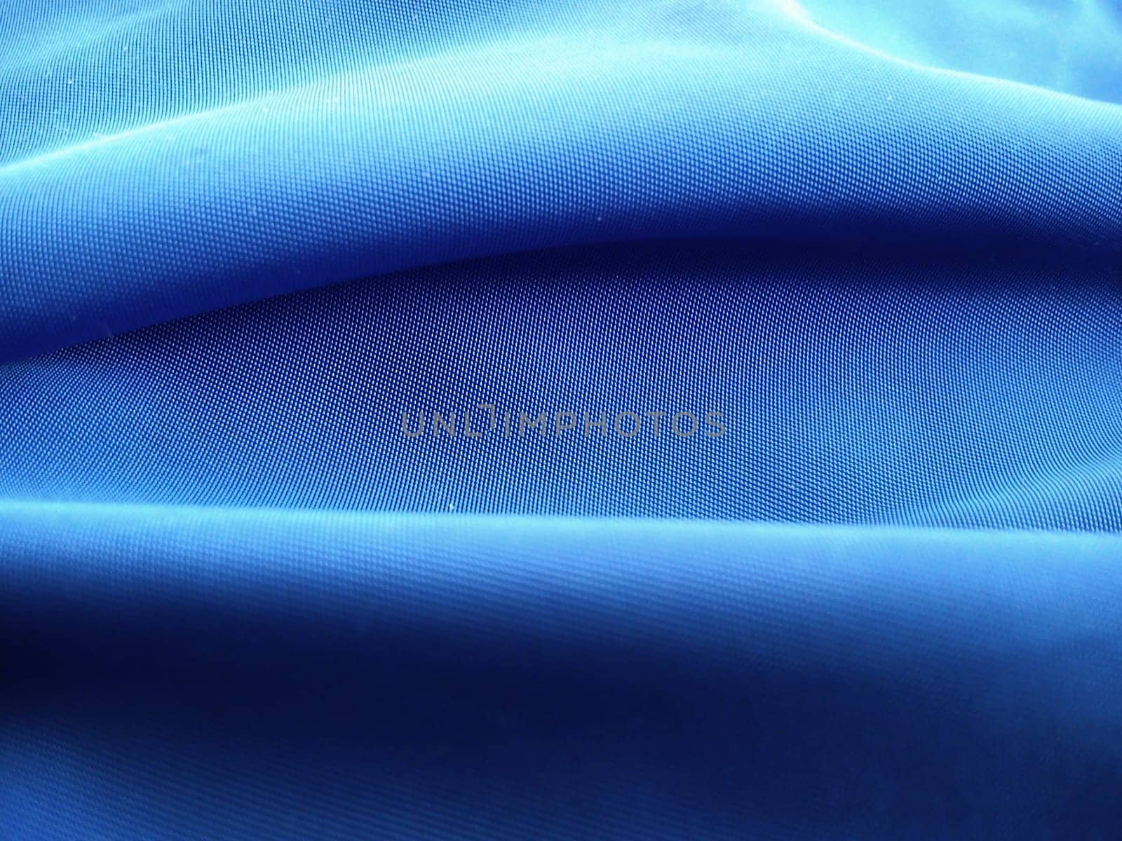 Blue fabric at close range, laid in horizontal waves. Abstract image in shades of blue
