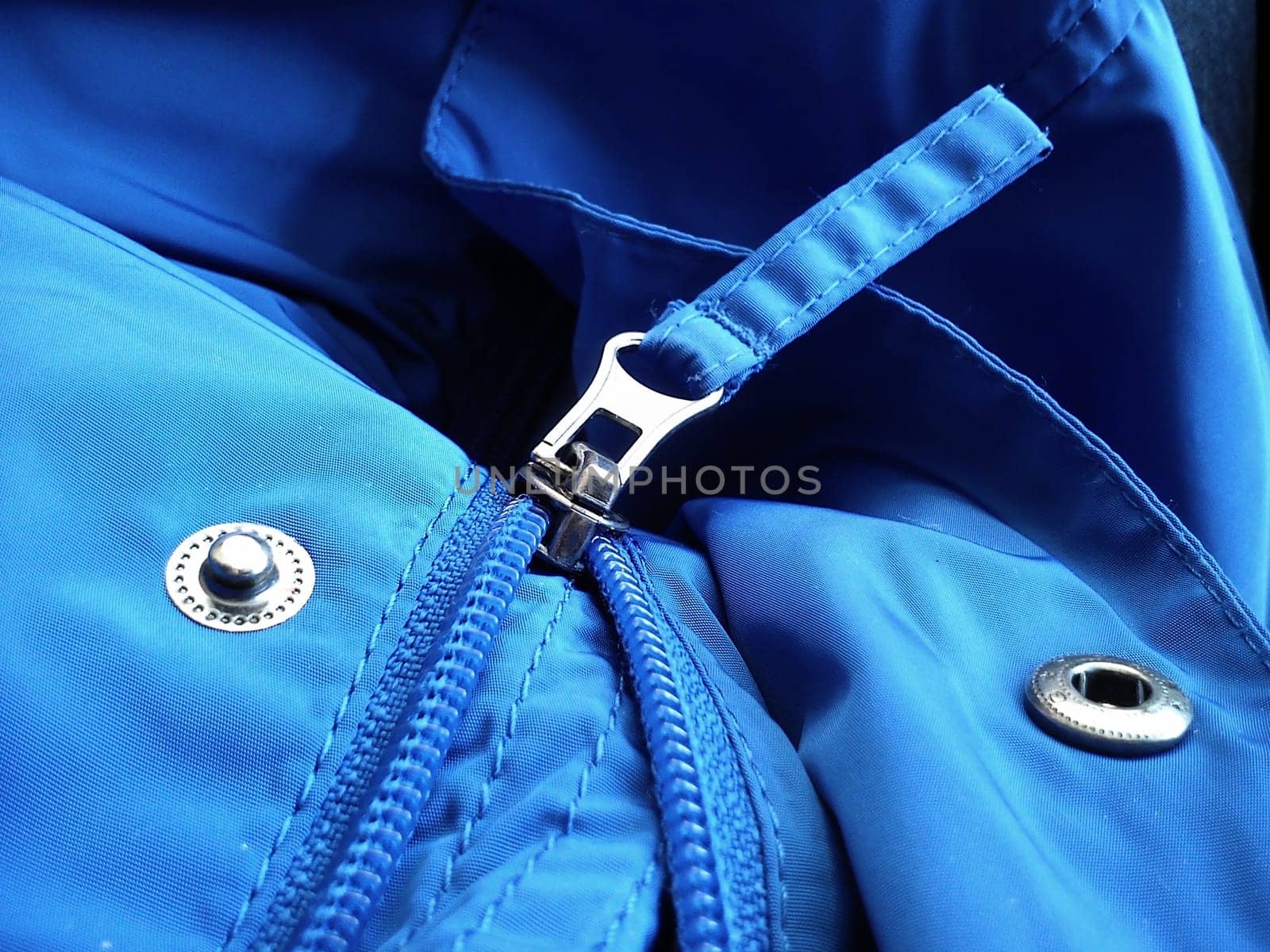 Half-open sewing lock on a blue synthetic fabric jacket. Open sewing buttons.