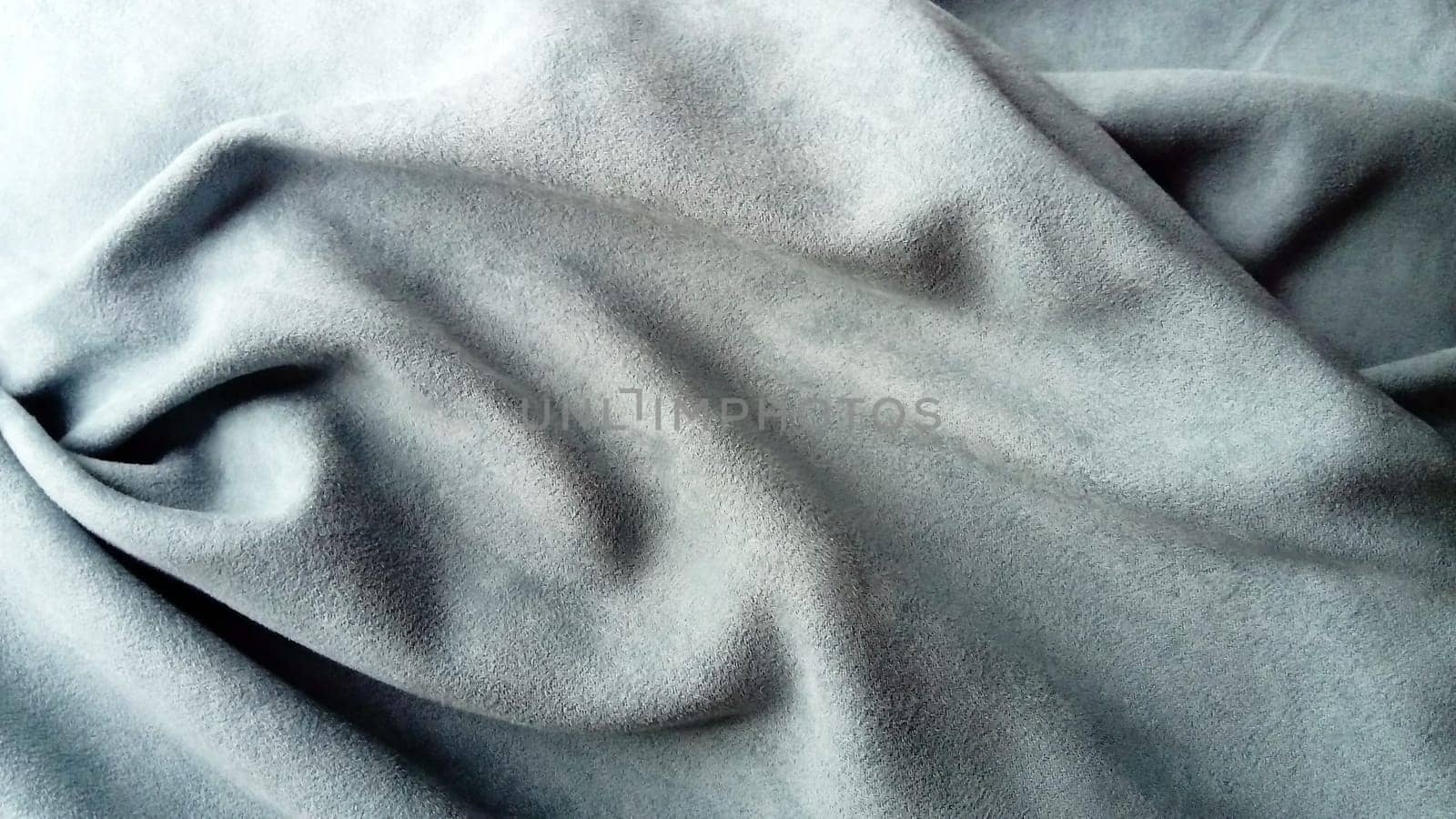 Canvas made of velvet fabric in gray, blue and asphalt. The fabric is laid in beautiful waves, reminiscent of a satire mask from afar. Theater curtain.
