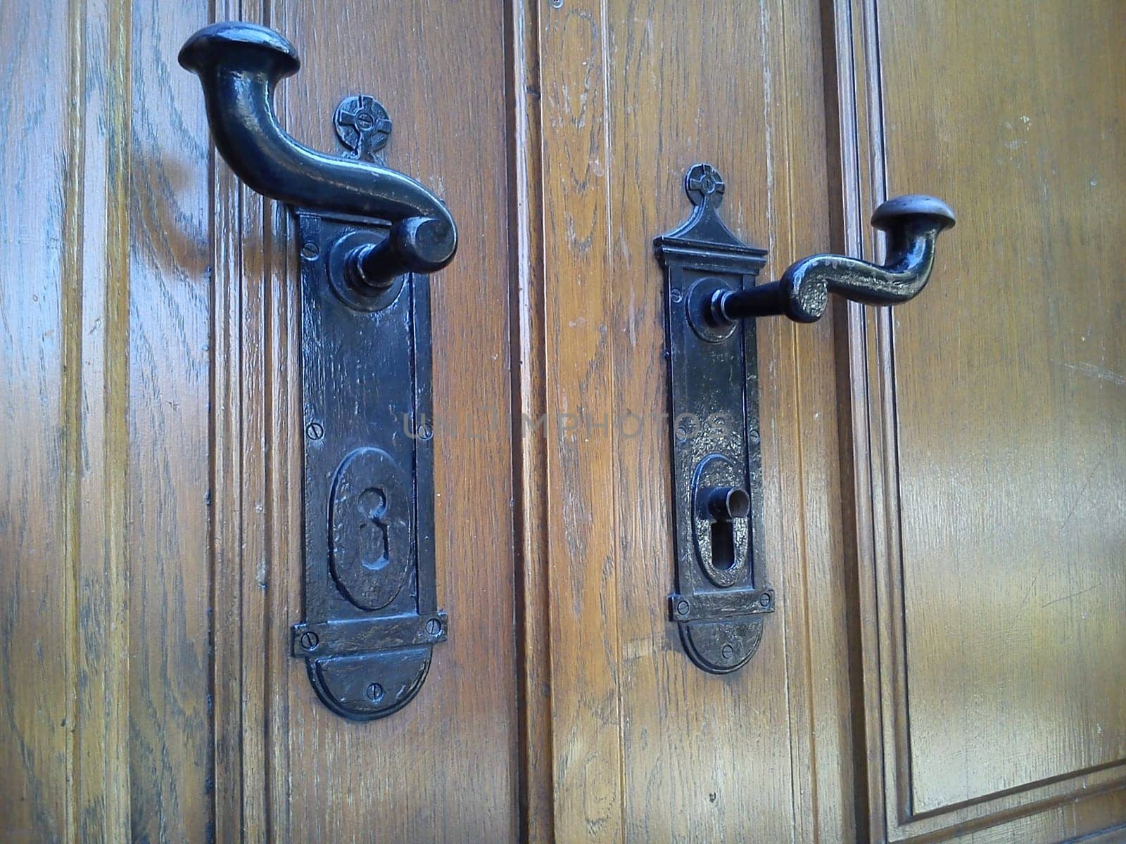 Forged metal door handles with a lock in a vintage design. The lock in the church door or in the door of the old house.