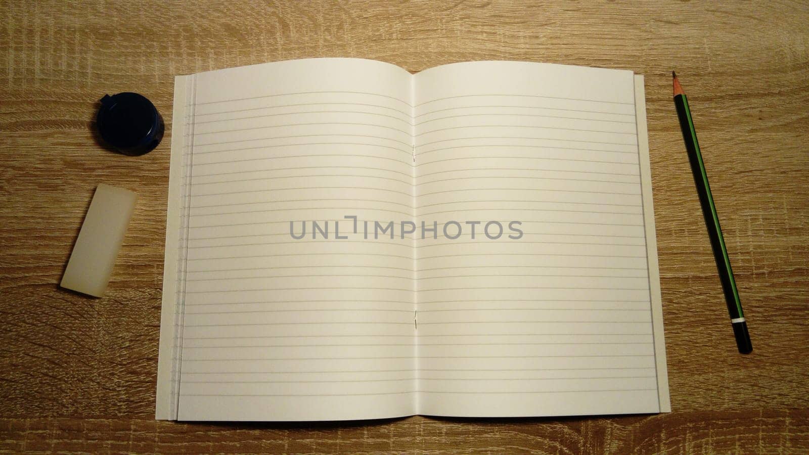U-turn notebook with white blank sheets. On the left are a pencil sharpener and eraser. Pencil on the right