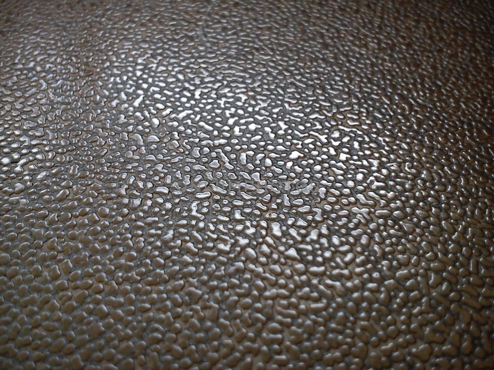Close-up of the surface of a plastic seat. Pimples of different sizes and backgrounds reflect daylight
