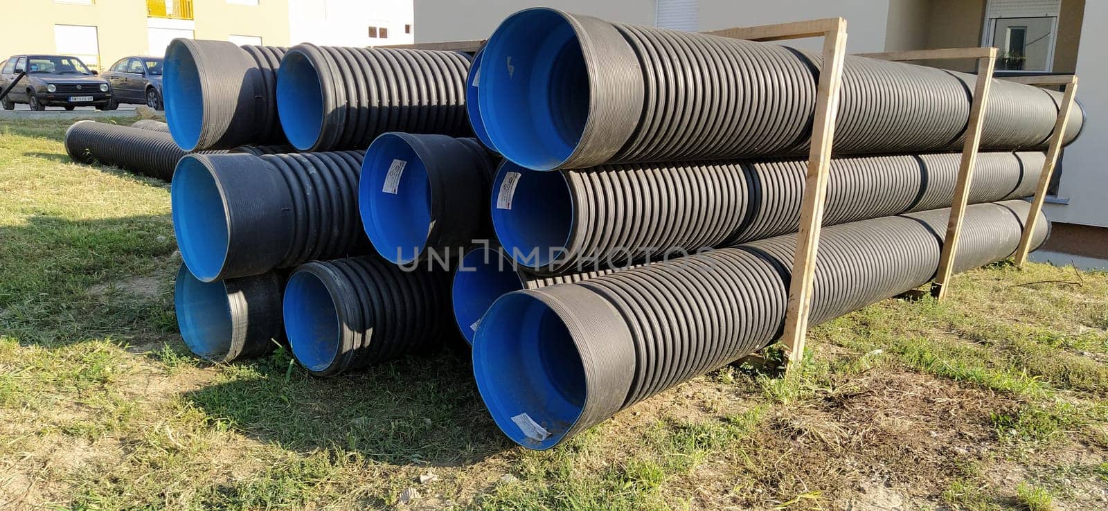 Sremska Mitrovica, Serbia, 23 August 2020. Metal corrugated pipes, blue inside. Plumbing or heating pipes lie on the ground next to a residential building. Corrugated metal.