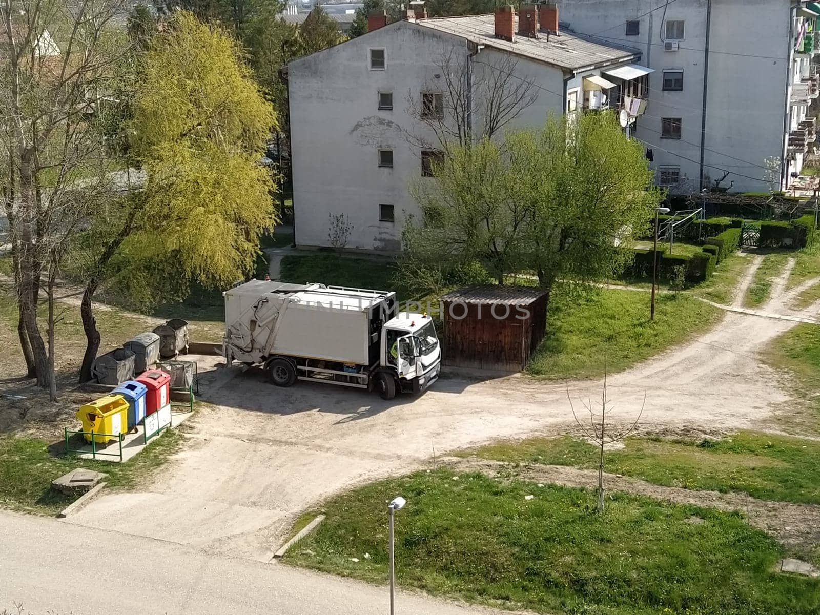 Sremska Mitrovica, Serbia, June 1, 2020. Garbage truck on the city street. Municipal and city services. Waste management and disposal. Car pulling up at the trash cans.