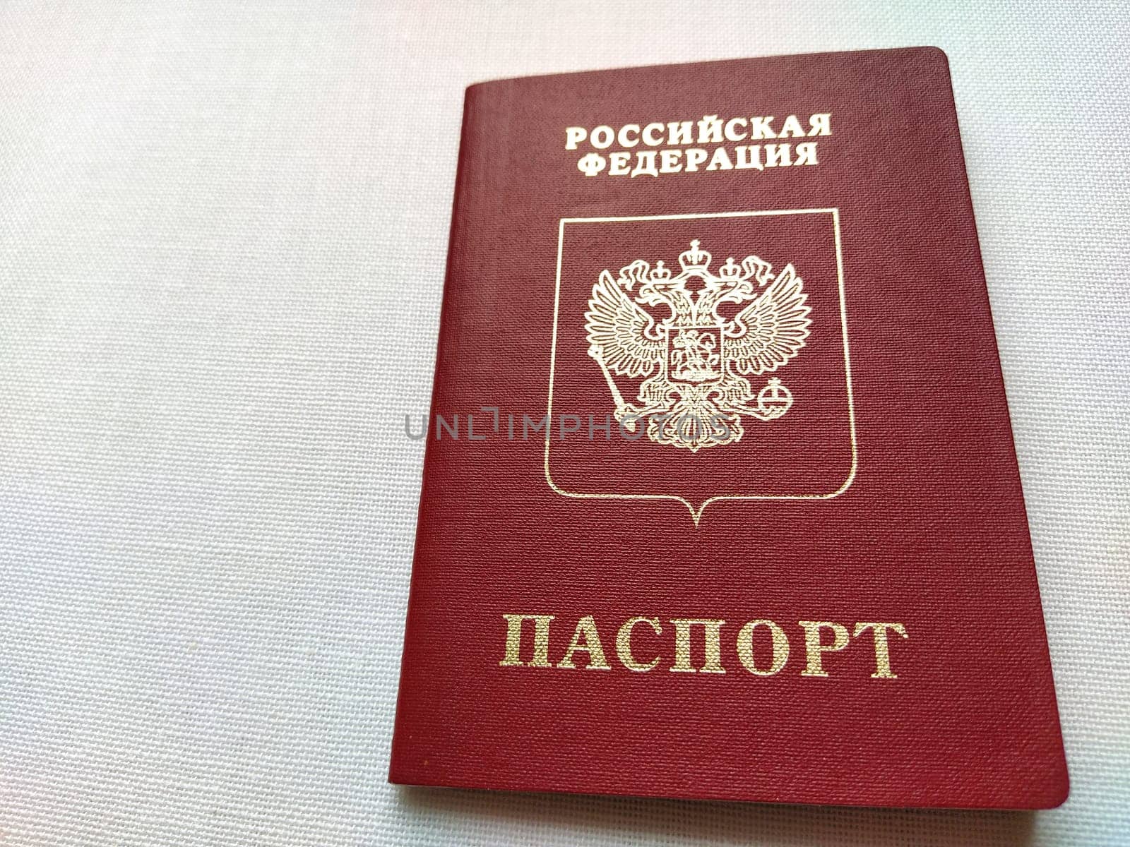 Passport of a citizen of the Russian Federation. International passport for travel and border crossing. Burgundy document cover with embossed gold letters. White background from textile.