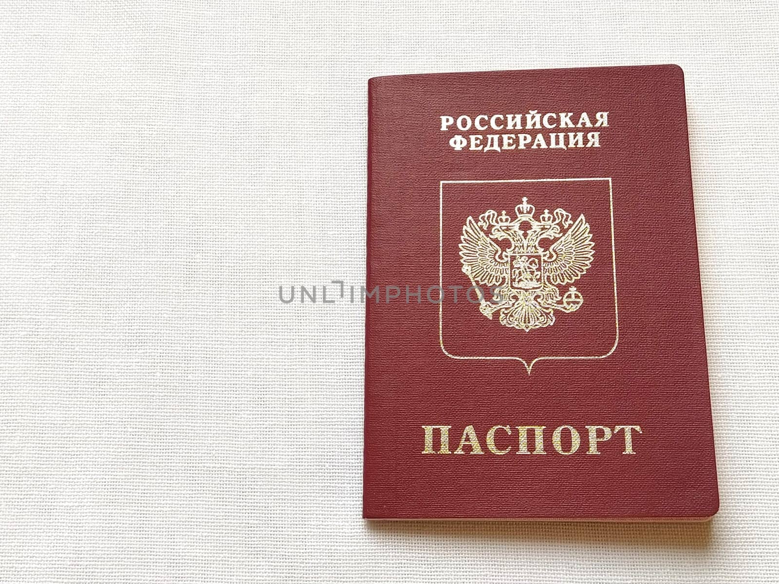 Passport of a citizen of the Russian Federation. International passport for travel and border crossing. Burgundy document cover with embossed gold letters. White background from textile.