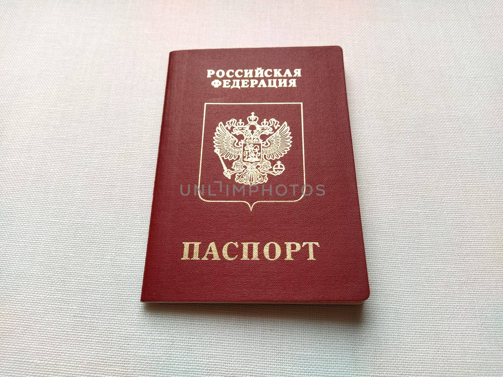 Passport of a citizen of the Russian Federation. International passport for travel and border crossing. Burgundy document cover with embossed gold letters. White background from textile.