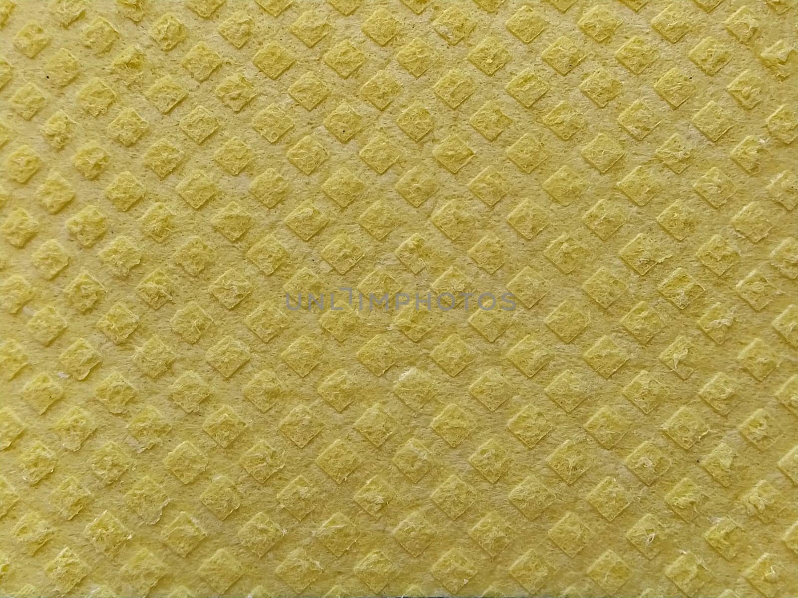 Close-up of fabric with embossed convex print. Bulging diamonds on yellow microfiber or dishwashing sponge. Background and free space for text.