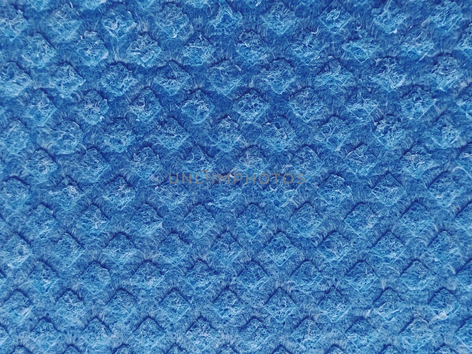 Close-up of fabric with raised raised print. Convex diamonds on blue microfiber or dishwashing sponge. Background and free space for text.