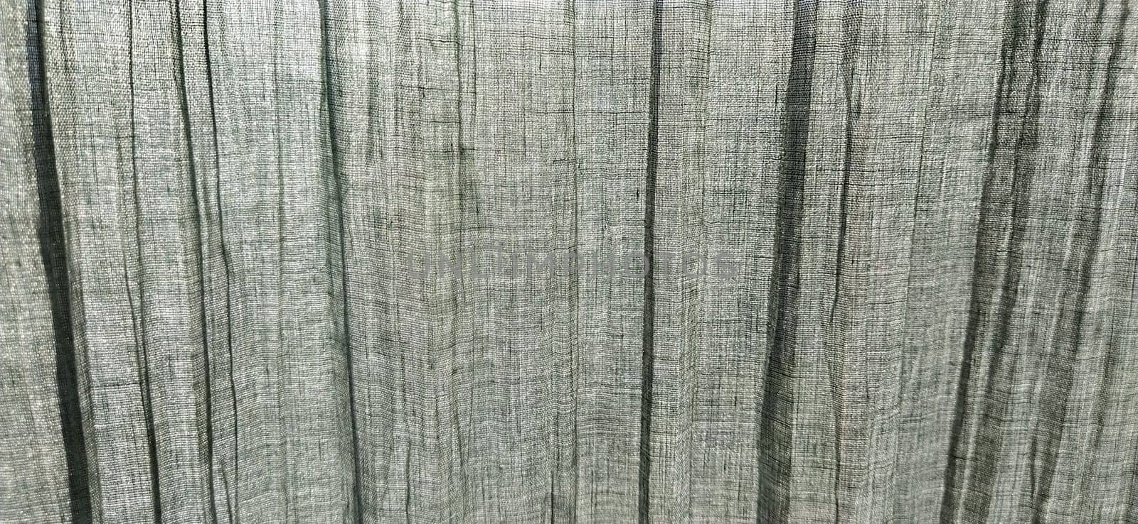 Gray pleated fabric or crumpled textile closeup. Light translucent curtains or tulle in the Scandinavian style. Soft focus. Pastel colors on the fabric.