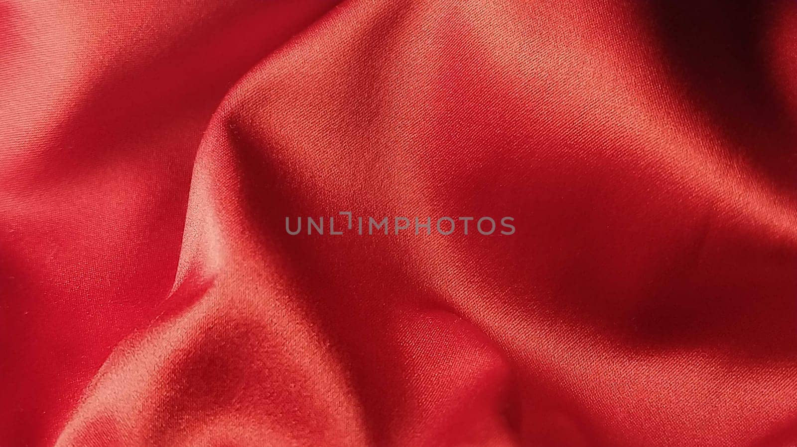 Closeup of ripples in red silk or satin fabric. Red Fabric cloth textured background in minimal modern style. Backdrop. Background for celebration, ceremony, event invitation card, advertising poster.