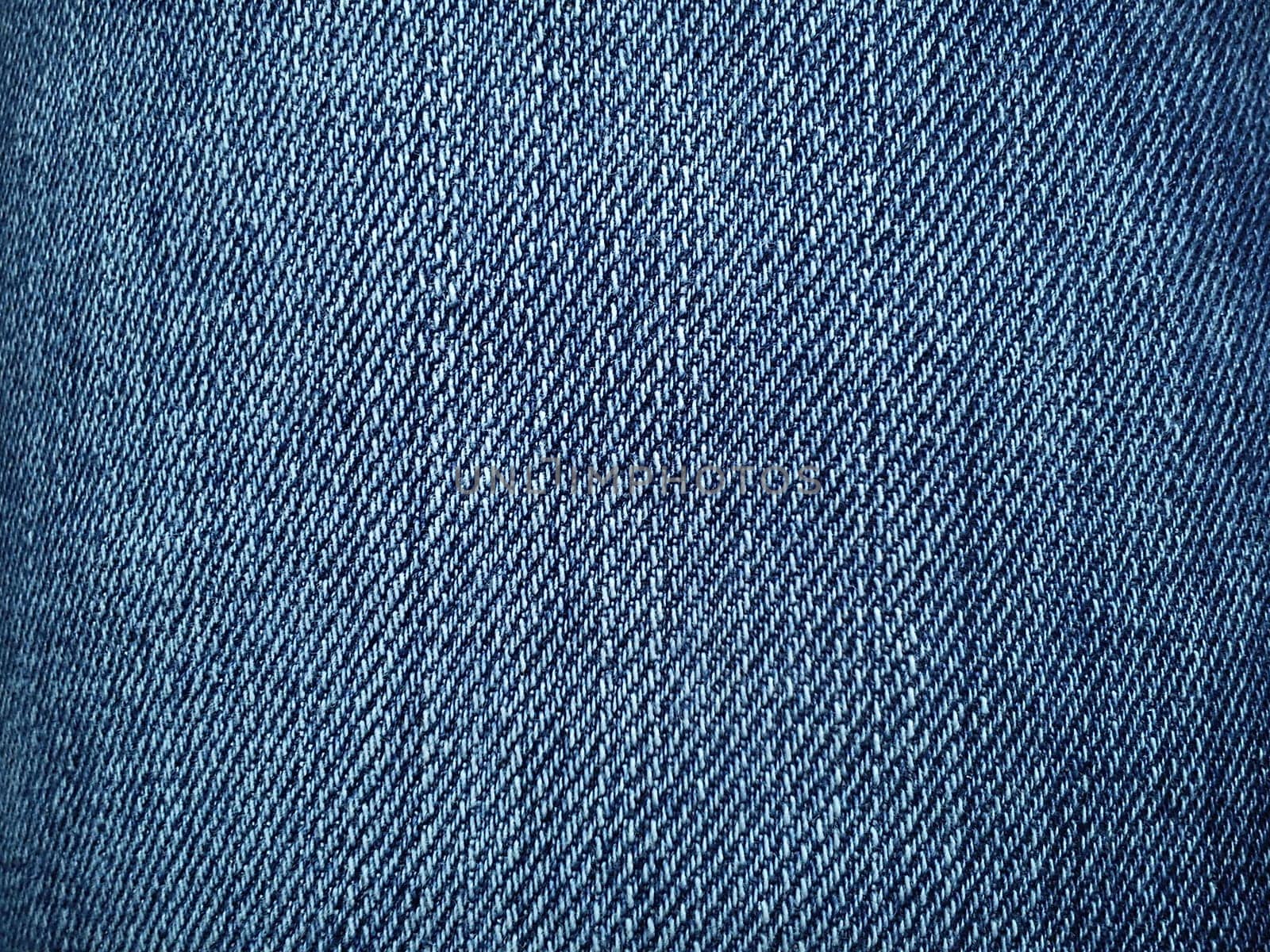 Blue denim. Texture of cotton coarse material. A fragment of a natural rag indigo. Vertical furrows, dark and light threads, individual stitches are noticeable.