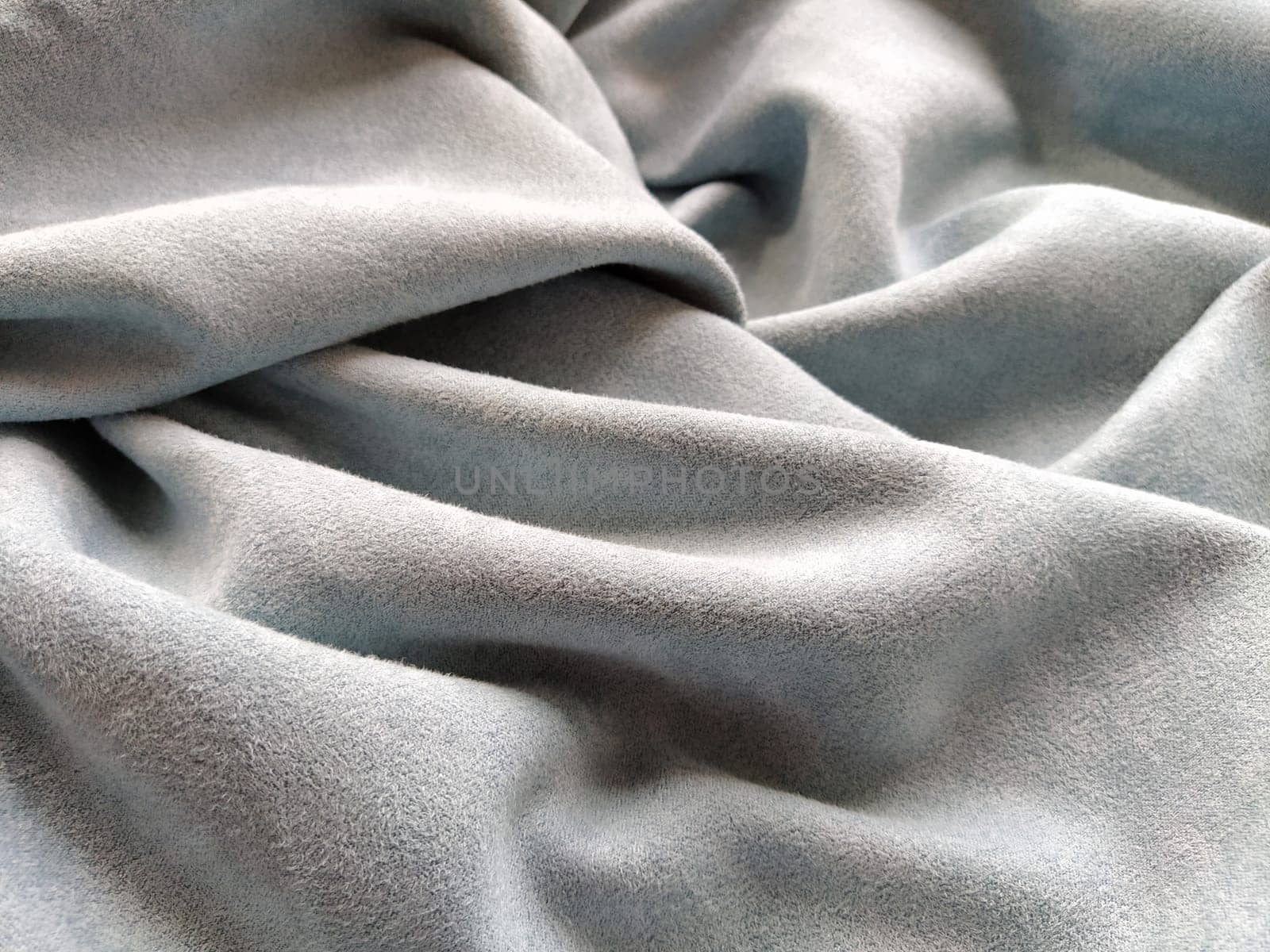 Fabric sheer curtain fabric. Beautiful gray-blue color. Soft velvet with a pile. The curtain material is carelessly folded and wrinkled on a horizontal surface. Fabric sample. Interior design option.