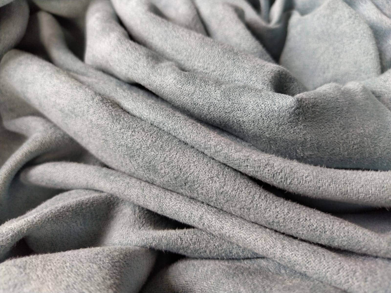 Fabric sheer curtain fabric. Beautiful gray-blue color. Soft velvet with a pile. The curtain material is carelessly folded and wrinkled on a horizontal surface. Fabric sample. Interior design option.