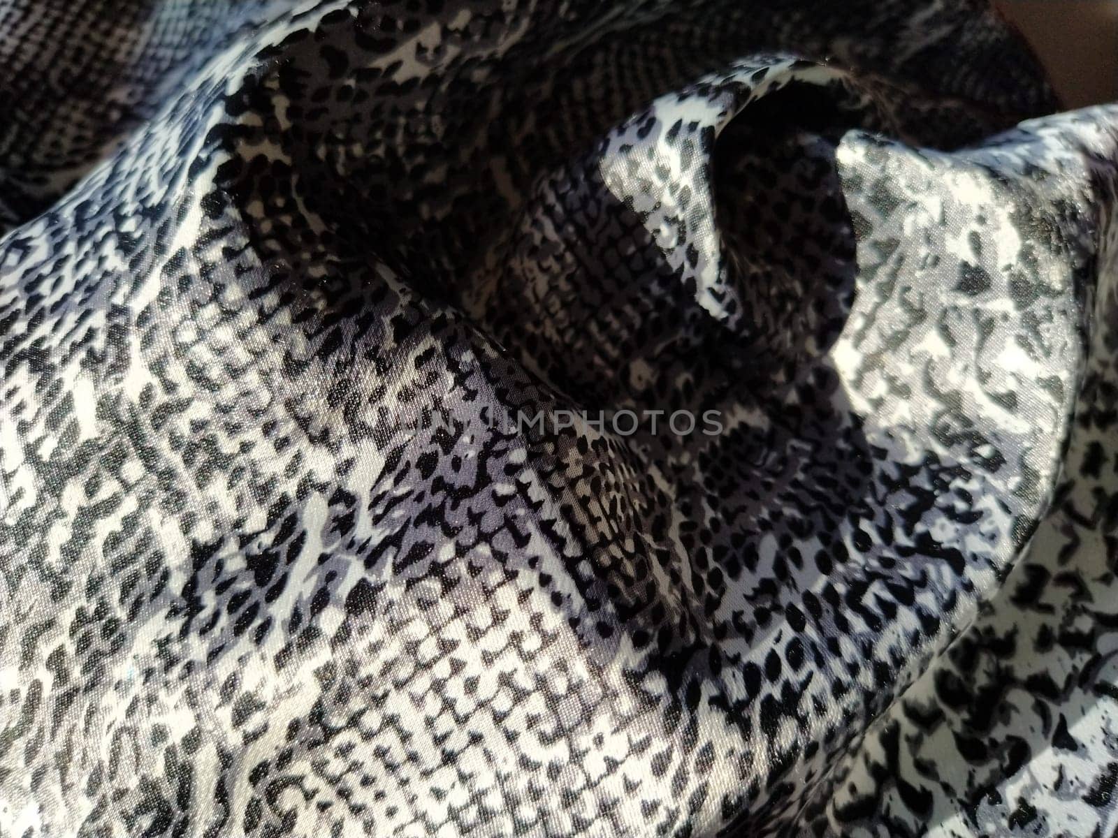 Crumpled silk gray spotted fabric. Pleasant shine of fabric, overflow of light is reflected in a piece of textile.