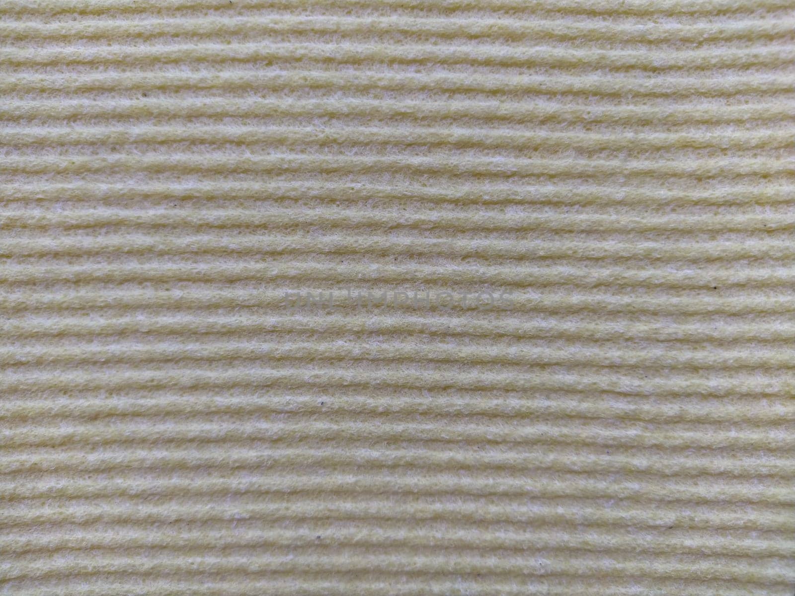 Beige or gray horizontal stripes. Dishwashing sponge or microfiber cloth close up. Soft focus.