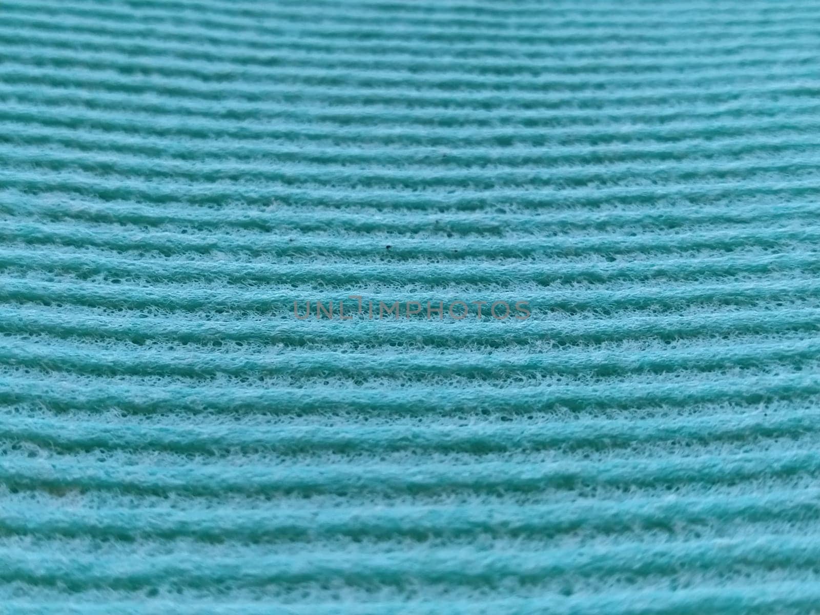 a green or aqua ribbed strip. Dishwashing sponge or microfiber cloth close-up. Soft focus.