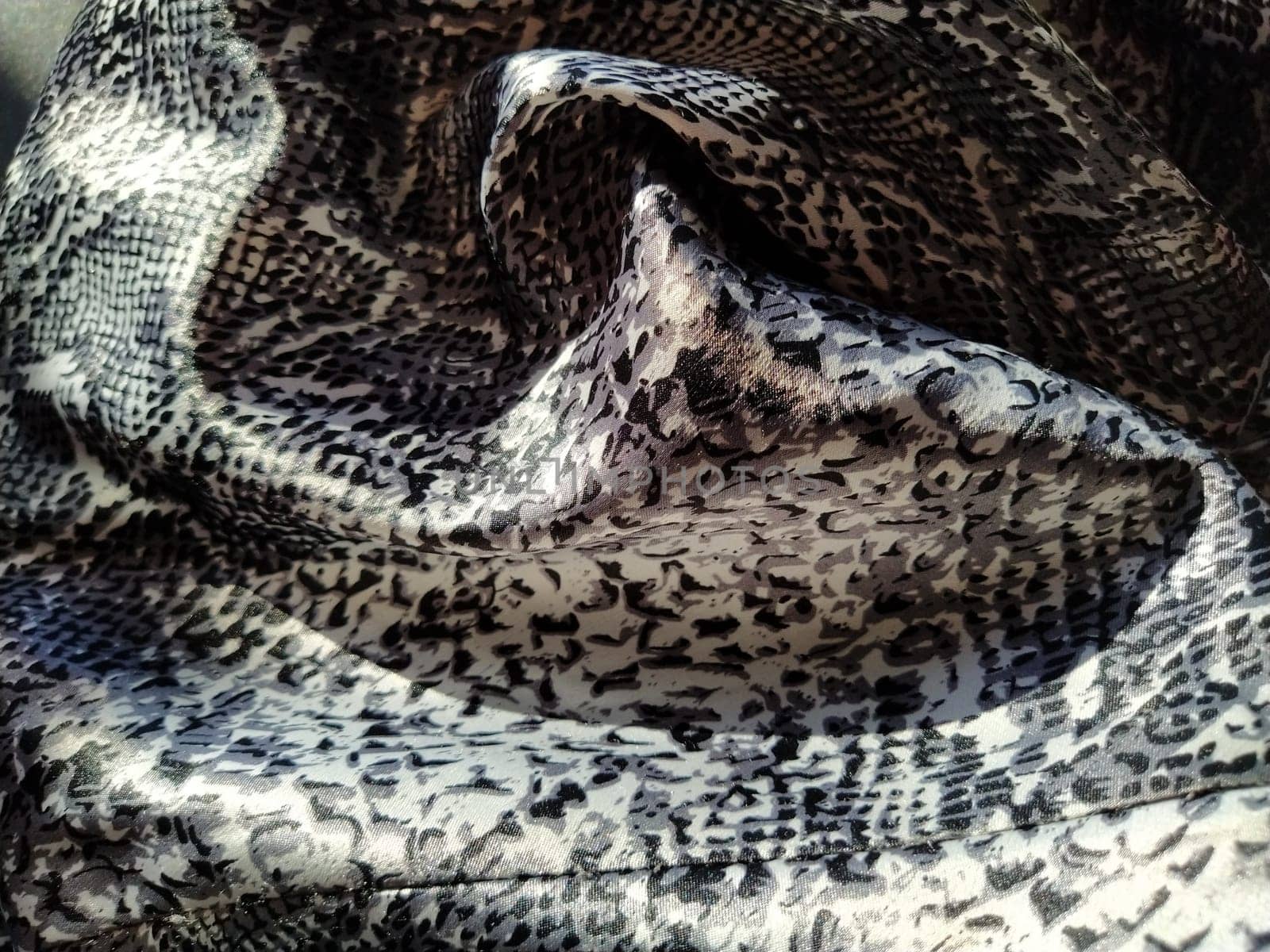 Crumpled silk gray spotted fabric. Pleasant shine of fabric, overflow of light is reflected in a piece of textile