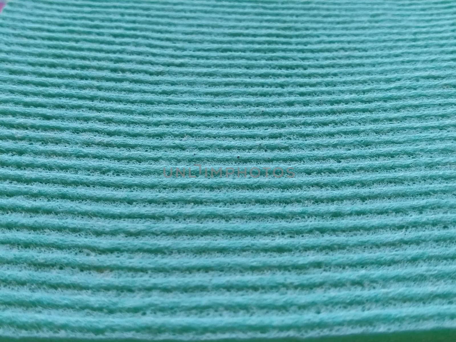 a green or aqua ribbed strip. Dishwashing sponge or microfiber cloth close-up. Soft focus.