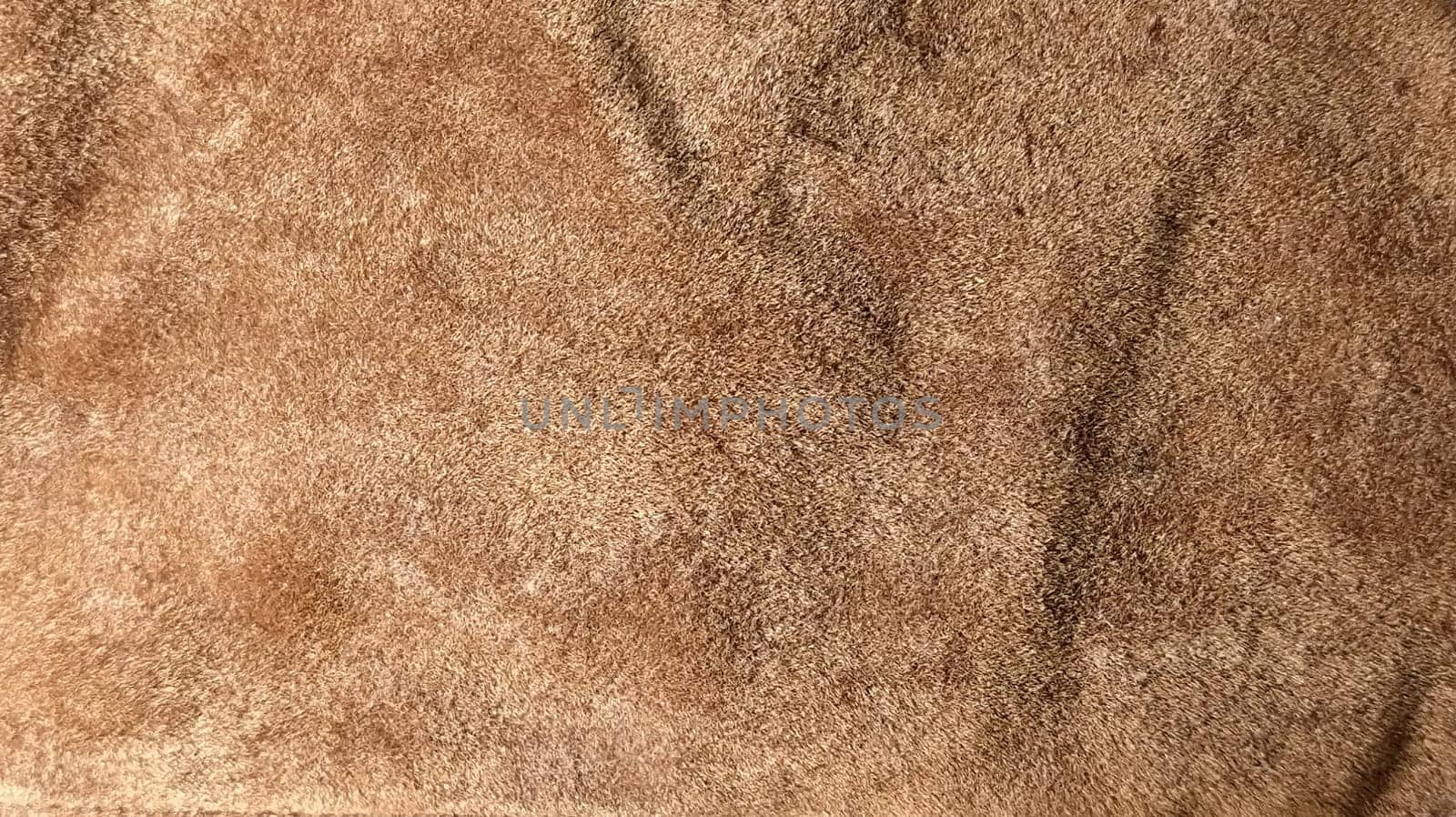 Brown and beige velvet. Close-up. Velvet fabric texture. Irregularities and overflows of light. Deep, rich, chocolate couloured satin. Folded and flowing background.