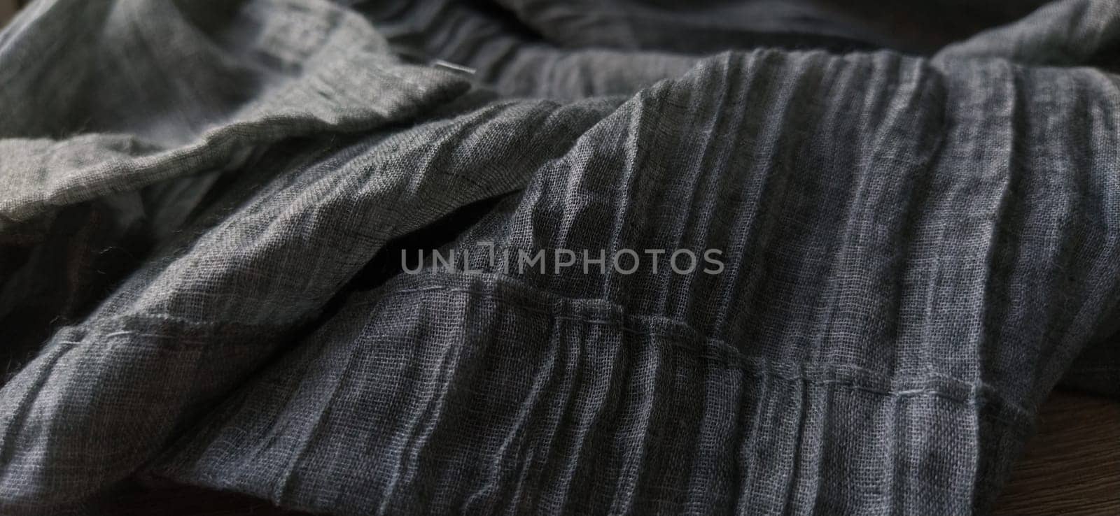Background of textile texture. Macro. Gray pleated fabric or crumpled textile closeup. Light translucent curtains or tulle in the Scandinavian style. Soft focus