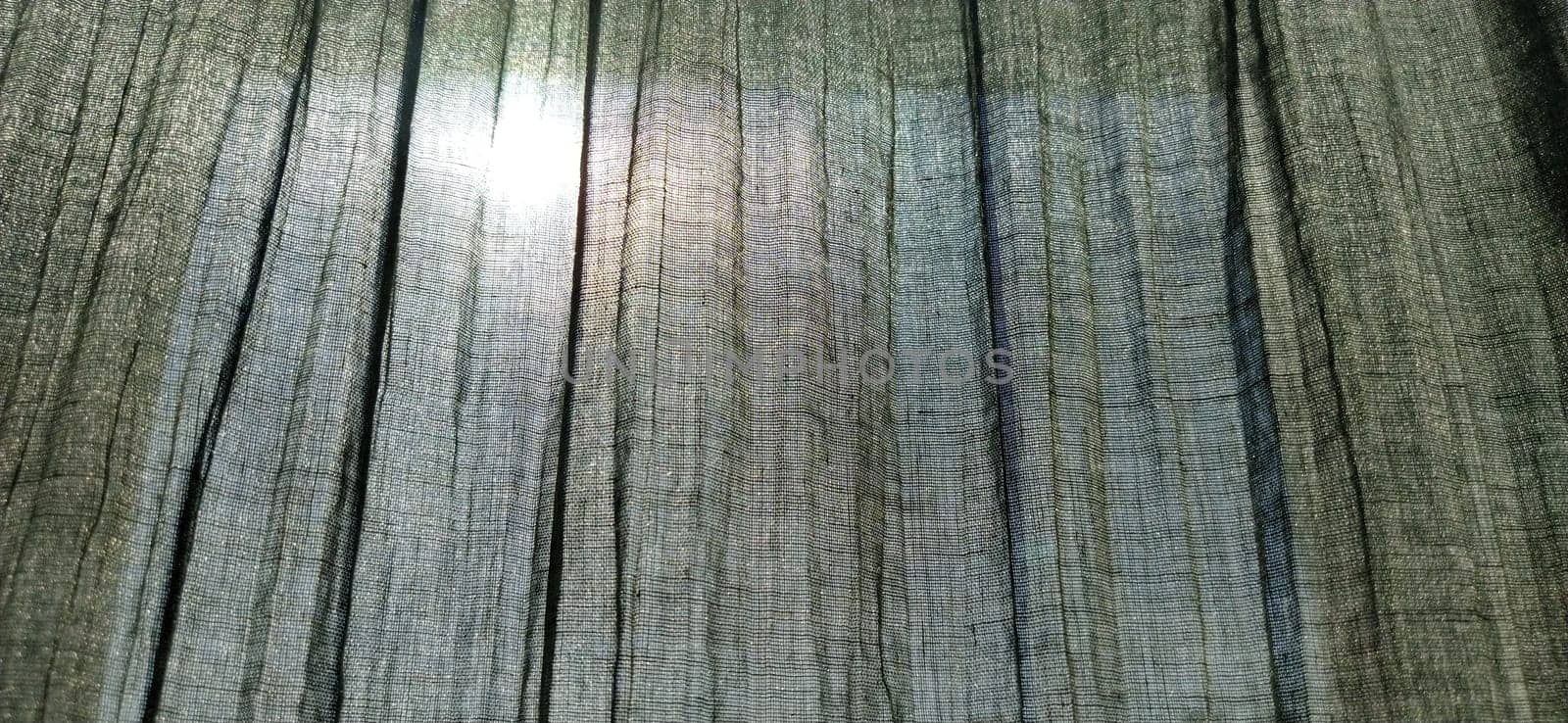 the sun is visible through the gray pleated curtains. Scandinavian style. Pastel colors on the fabric. The curtain is translucent, through which you can see what is happening on the street.