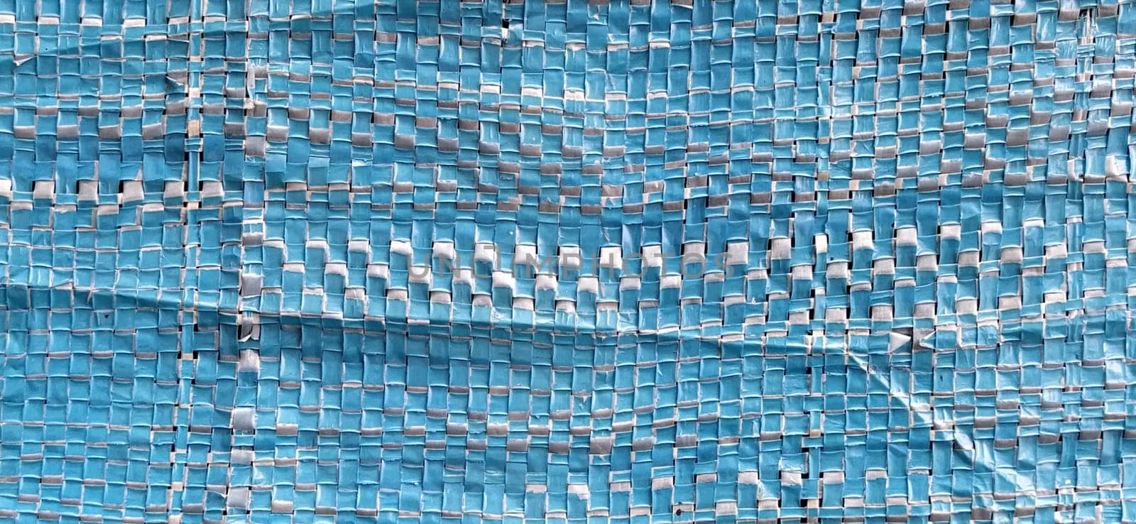 Blue synthetic burlap, close-up. Polyethylene material. Interlacing of polyethylene fibers and threads. Folds and bruises. Packing and packaging material.