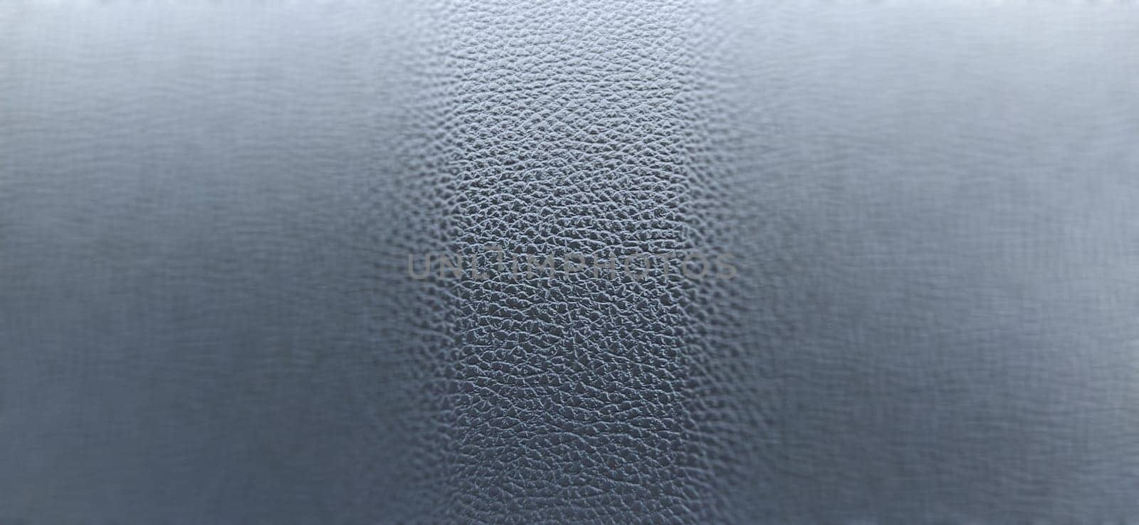 Black leather banner background with rich texture detail. close-up of black leather. A blurred background around the edges of the image. Artificial leather or polyester.