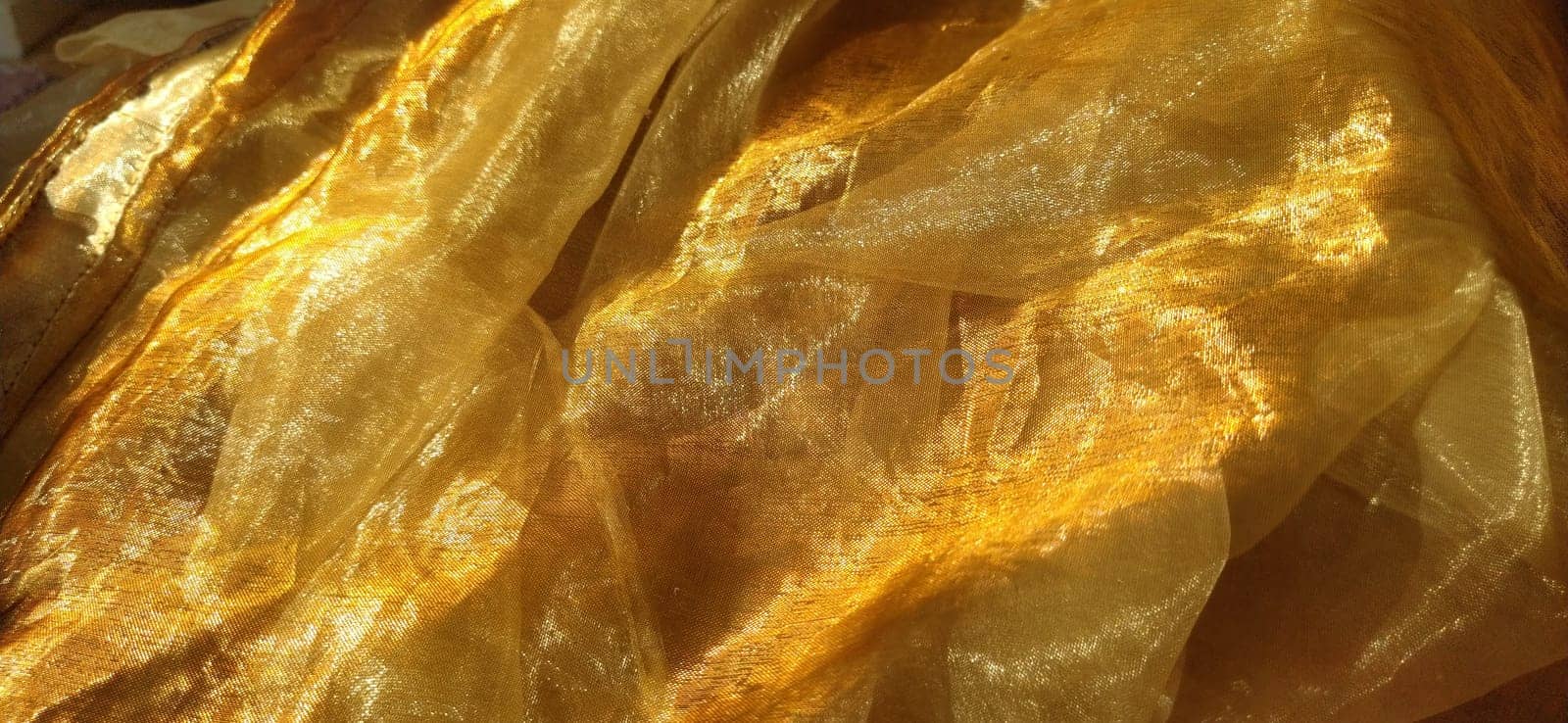Organza is yellow-brown with a beige sheen. Shiny, reflective, beautiful fabric for curtains, tulles. Interior design option. Twisted, casually folded organza. Banner.