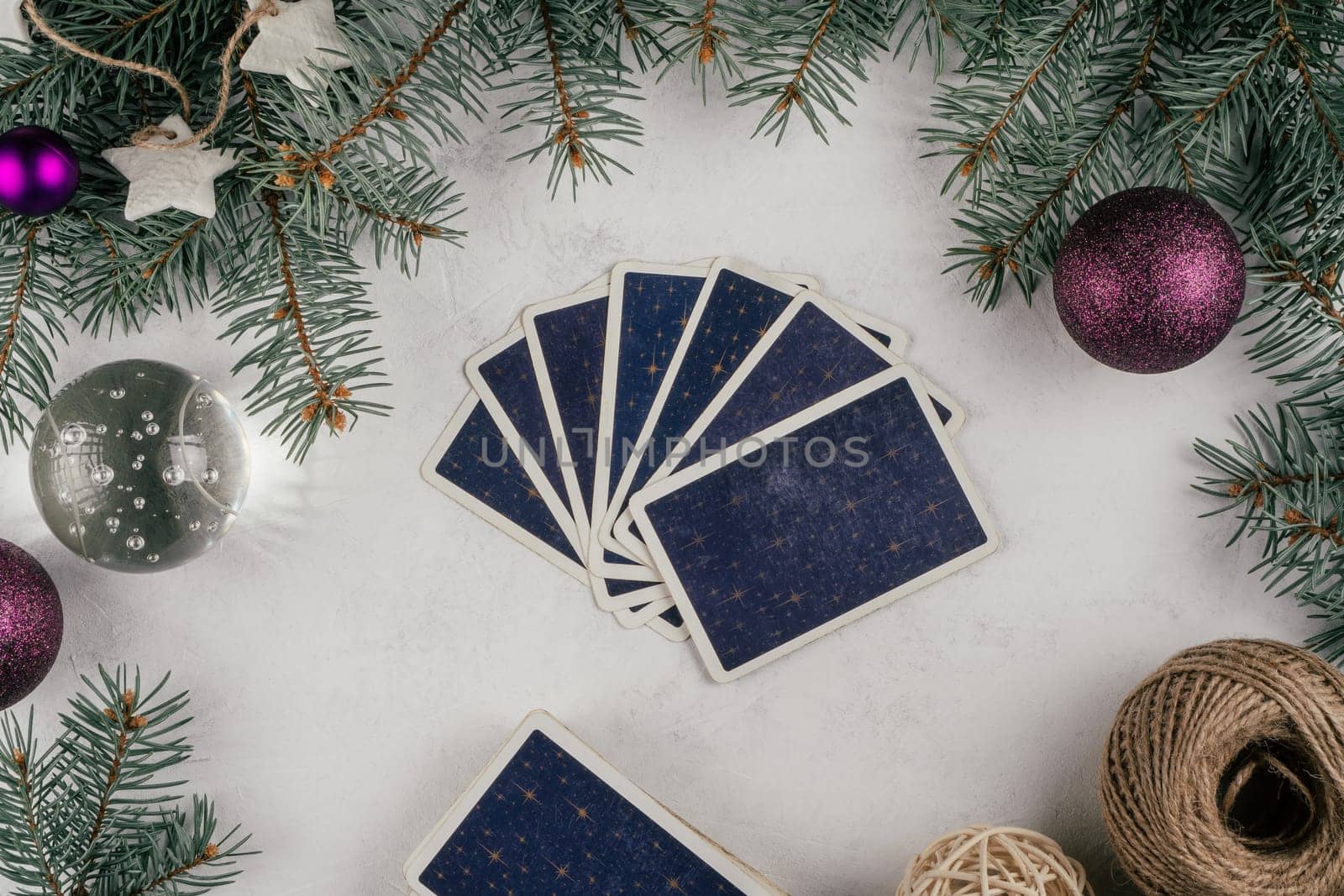 Tarot cards fanned back up on white concrete surface with Christmas tree branches and decorations. Minsk, Belarus, 19.11.2021