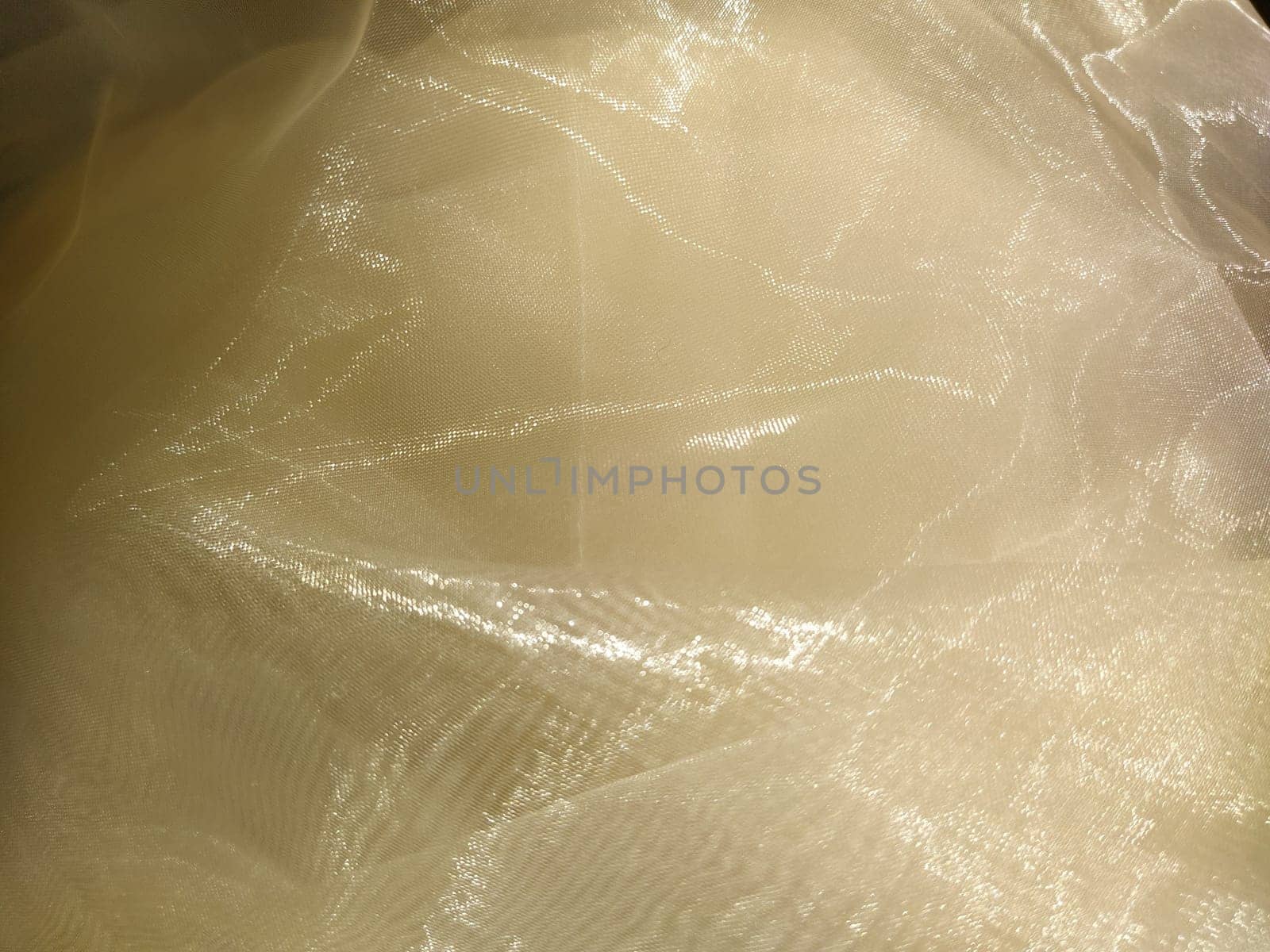 Organza in white and beige or champagne color close-up. Lightweight sheer tulle curtains under side lighting.