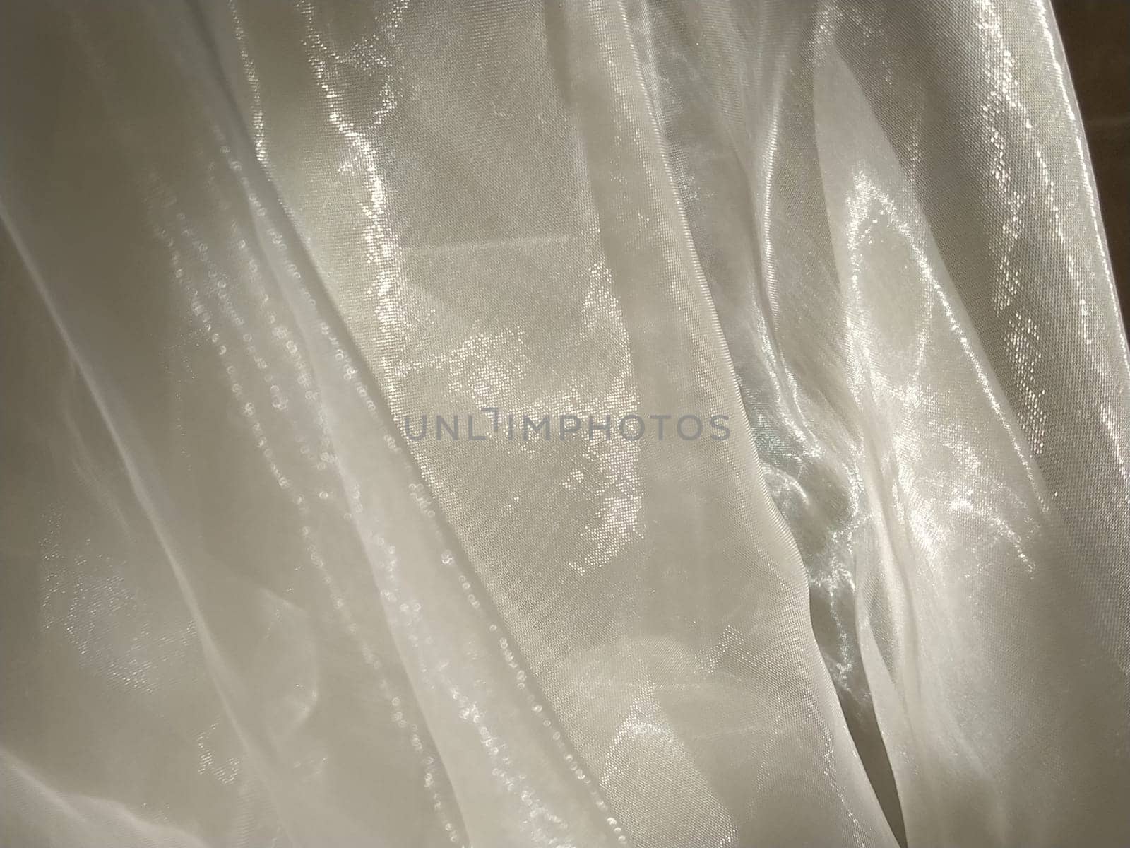 Organza in white and beige or champagne color close-up. Lightweight sheer tulle curtains under side lighting.