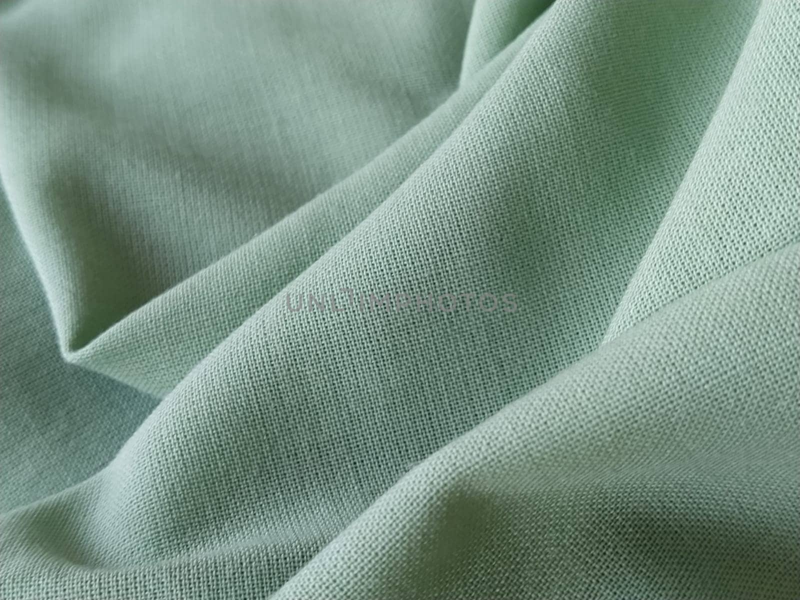 Close up of a woolen fabric of green color. Abstract canvas background, empty template. Thin natural fabric, wool or linen.