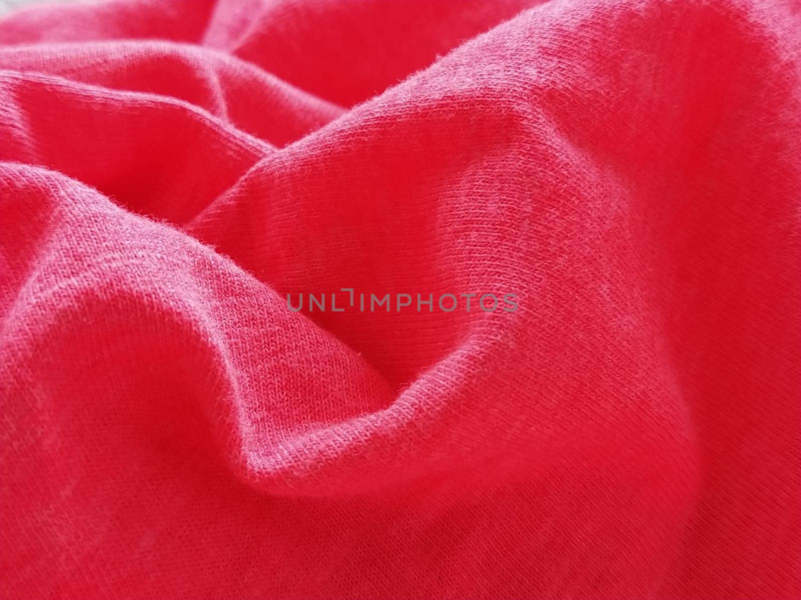 Bright pink or magenta polyester fabric, wrinkled or folded carelessly. Saturated background. Defocused photo around the edges of the photo