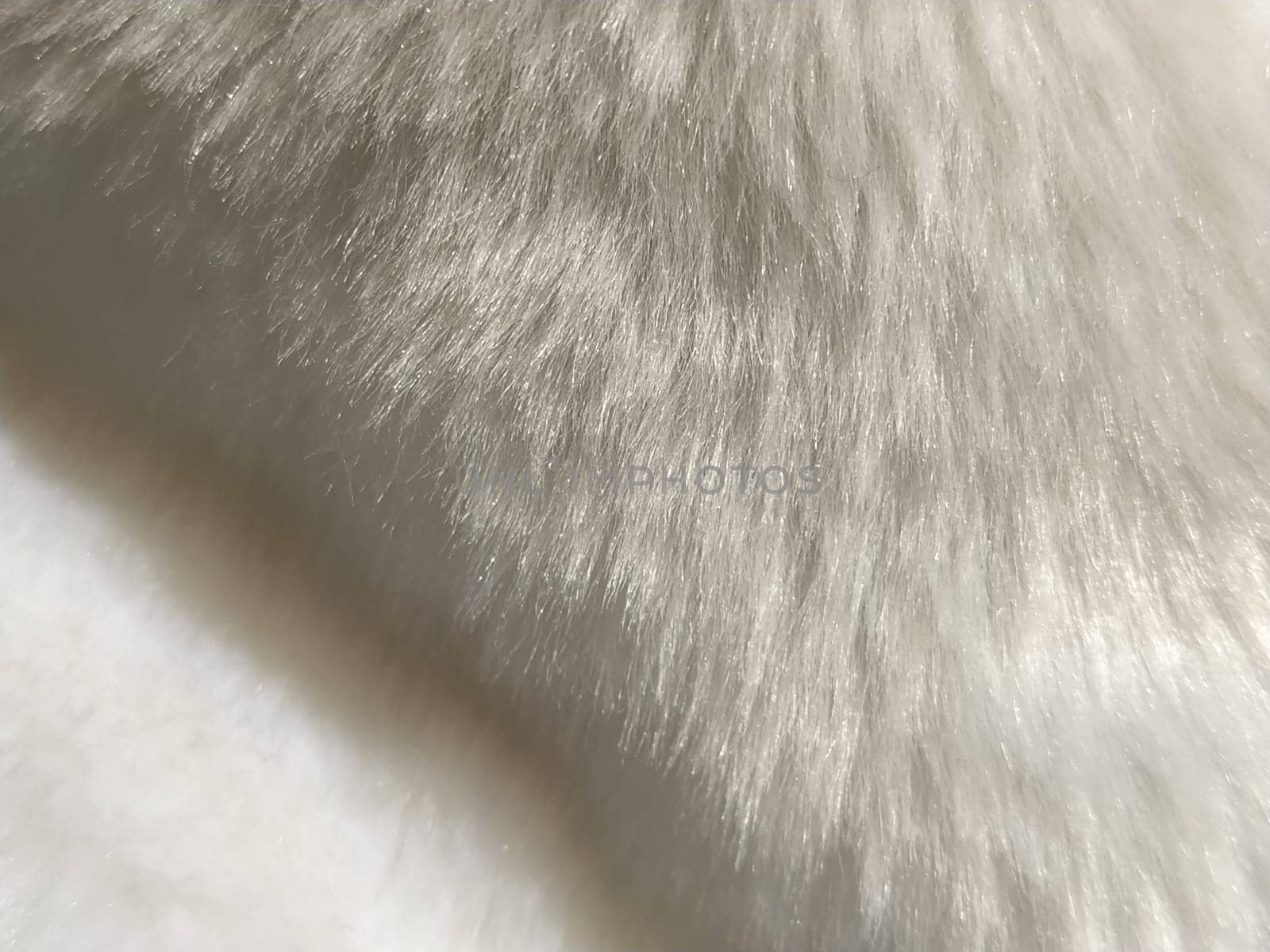 White faux fur. Close-up. Partially defocused photo. Fluffy villi.