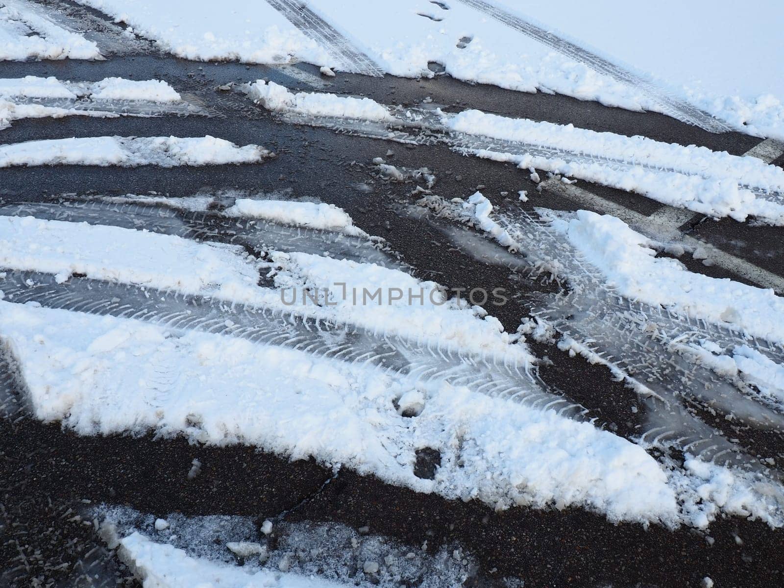Snowdrifts on the side of the road. Bad weather and traffic. Snow on asphalt. Difficult driving conditions. Winter slosh on the road. Braking distance of a car