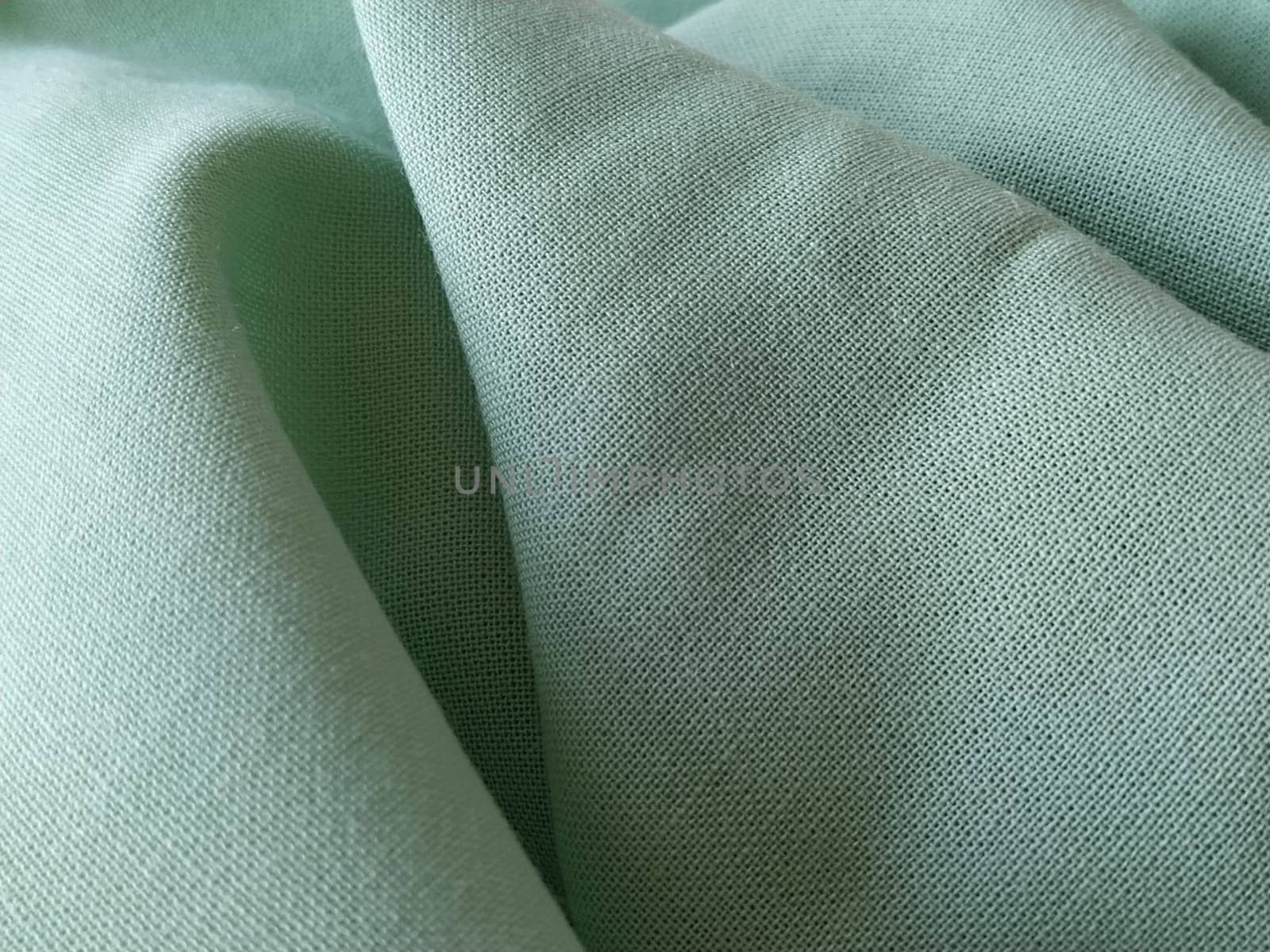 Close up of a woolen fabric of green color. Abstract canvas background, empty template. Thin natural fabric, wool or linen.