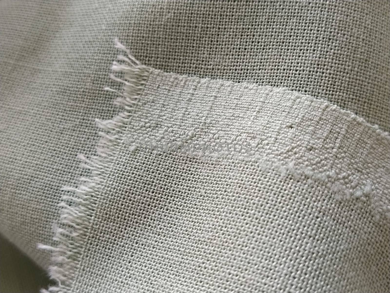 Close up of a woolen fabric of green color. Abstract canvas background, empty template. Thin natural fabric, wool or linen. The edge of the fabric is treated against chapping.