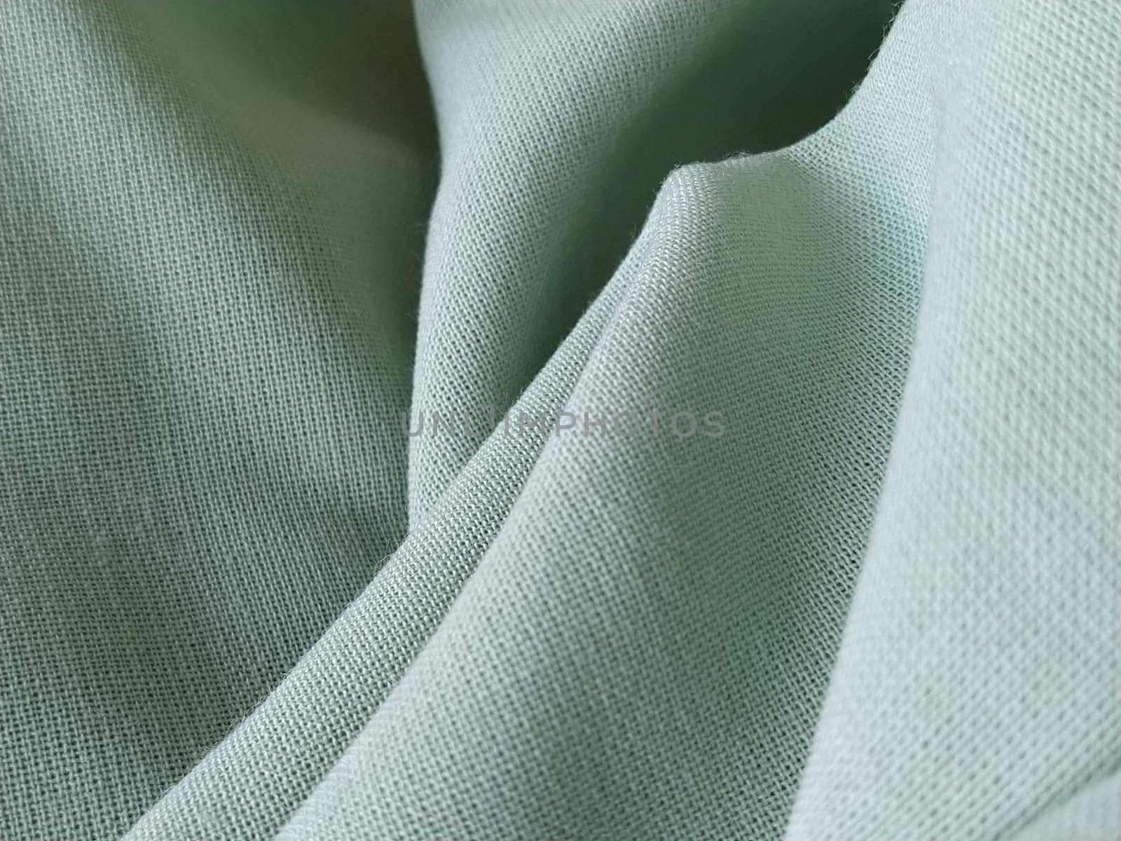 Close up of a woolen fabric of green color. Abstract canvas background, empty template. Thin natural fabric, wool or linen.