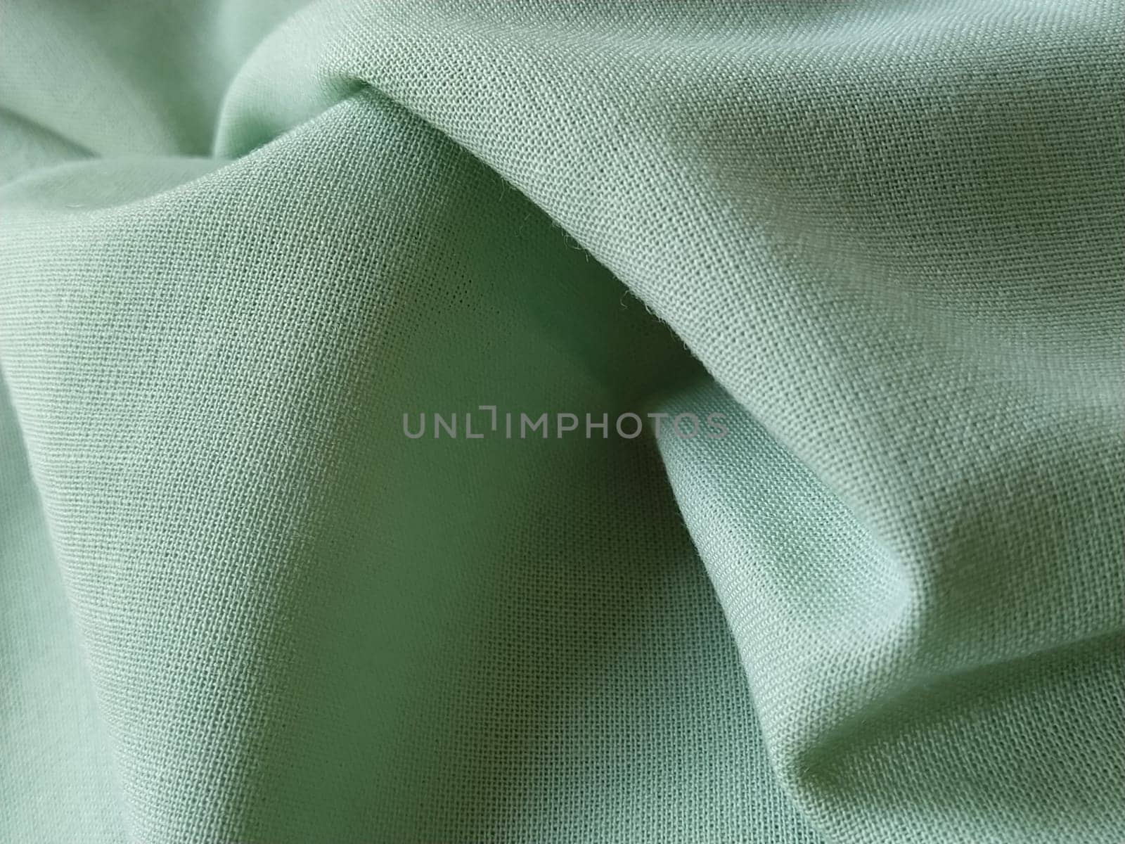 Close up of a woolen fabric of green color. Abstract canvas background, empty template. Thin natural fabric, wool or linen.