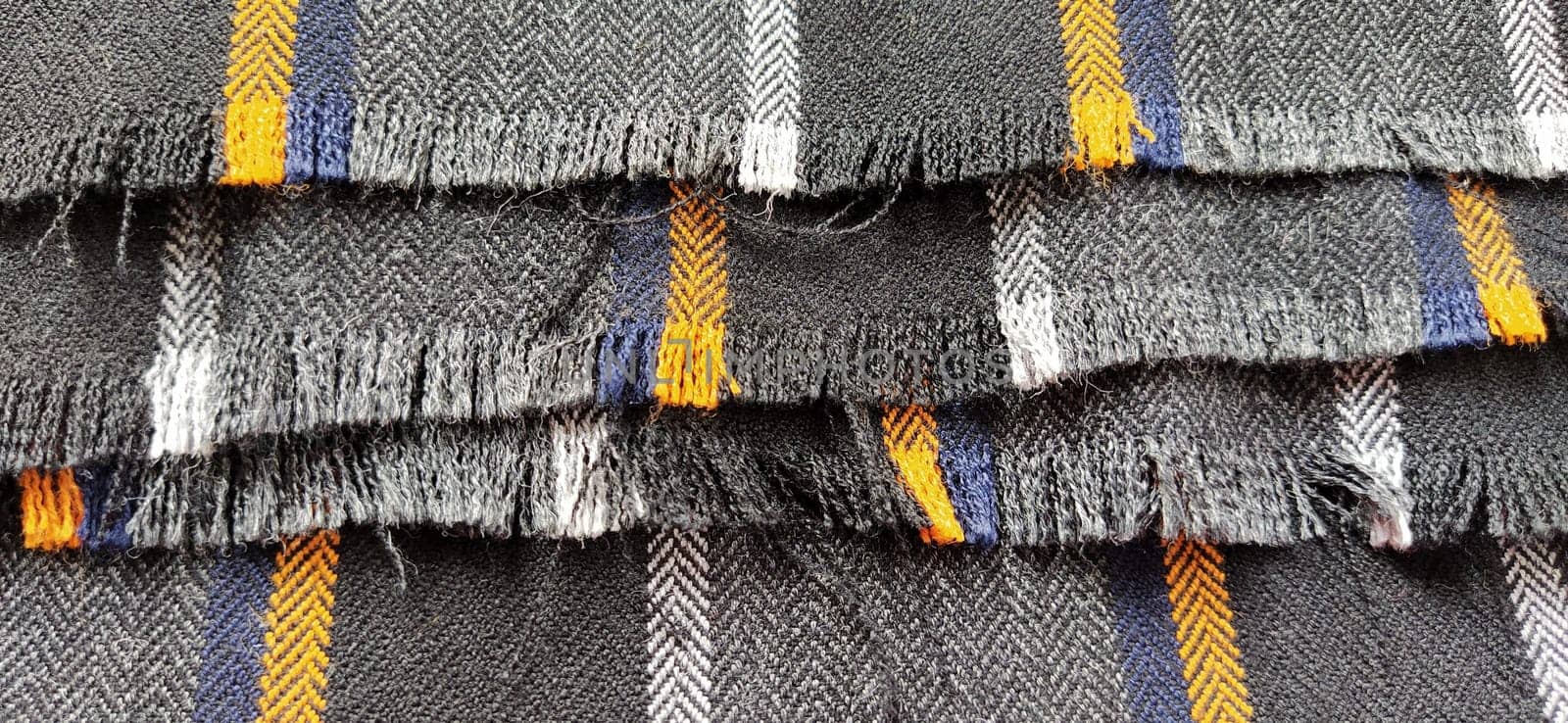 Gray-black fabric with orange and blue stripes. Textile fabric folded neatly on the surface. Natural wool material for sewing clothes and upholstery. Lifestyle. Close-up. Soft focus.