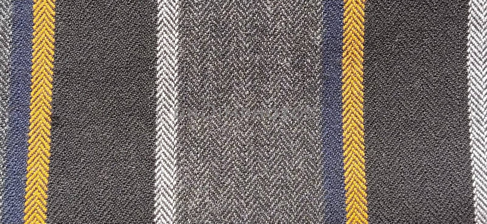 Gray-black fabric with orange and blue stripes. Textile fabric on the surface. Natural wool material for sewing clothes and upholstery. Lifestyle. Close-up. Soft focus.