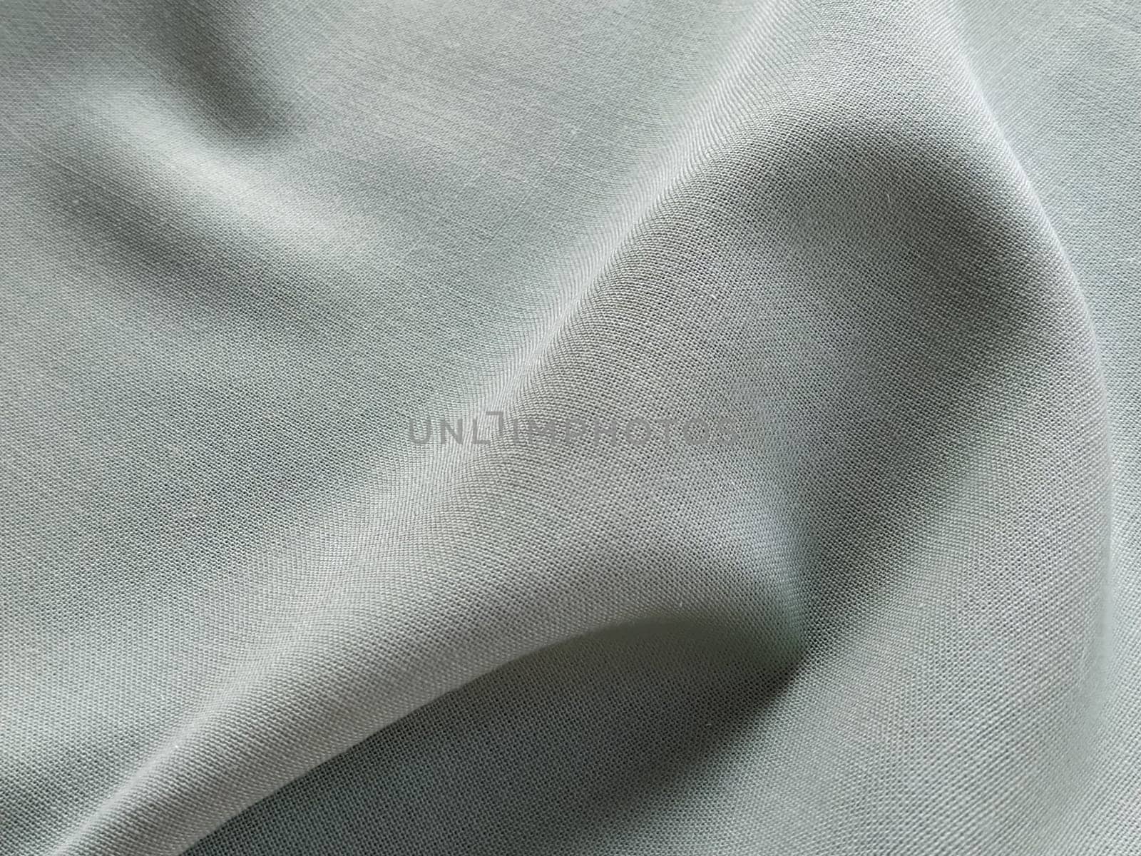 Beautifully folded light green fabric. Soft pleasant waves and flounces on textiles. Close-up. Drapery for curtains, fabric for dressmaking or upholstery.
